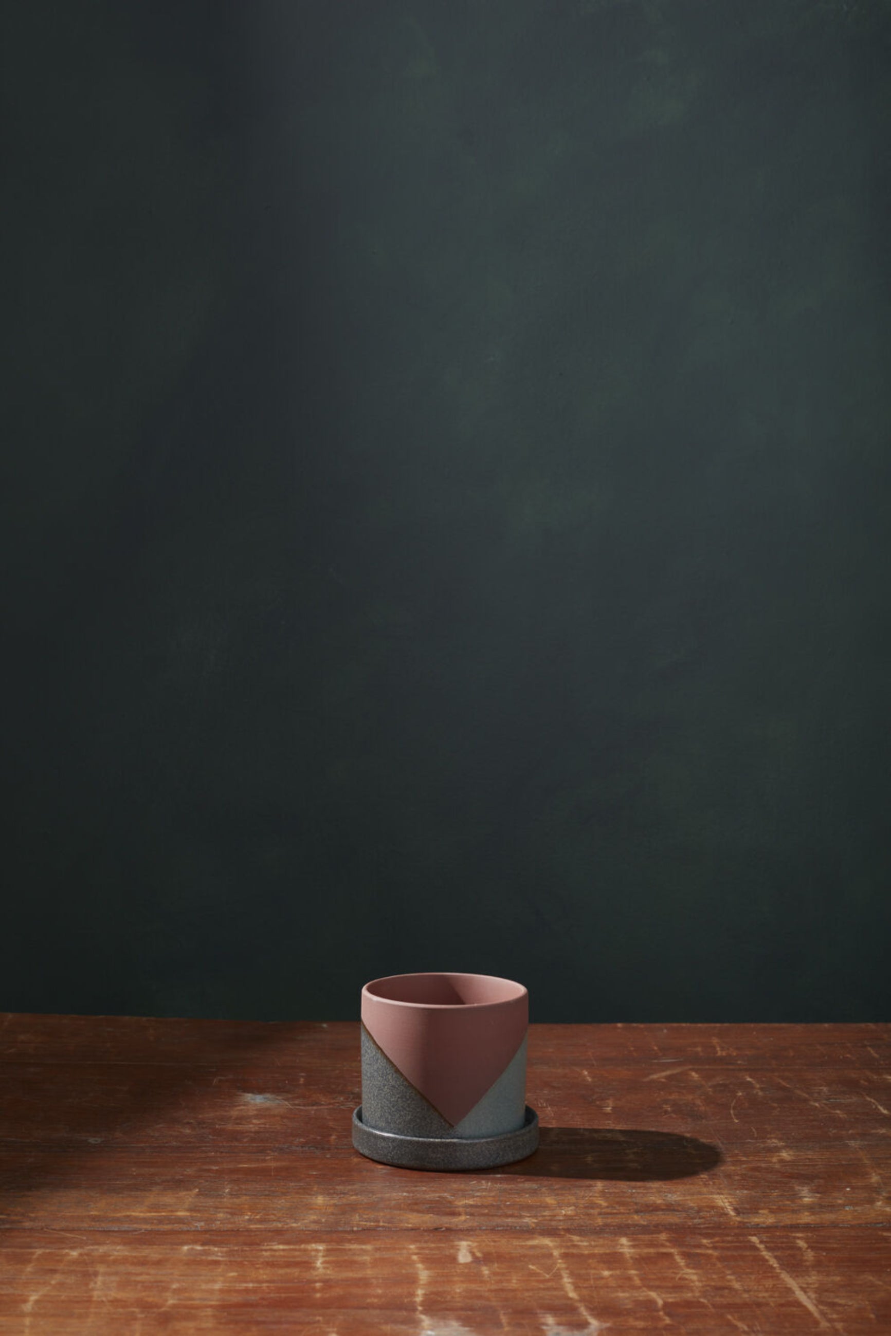 An empty El Cerro pot on a wood table and dark gray background.