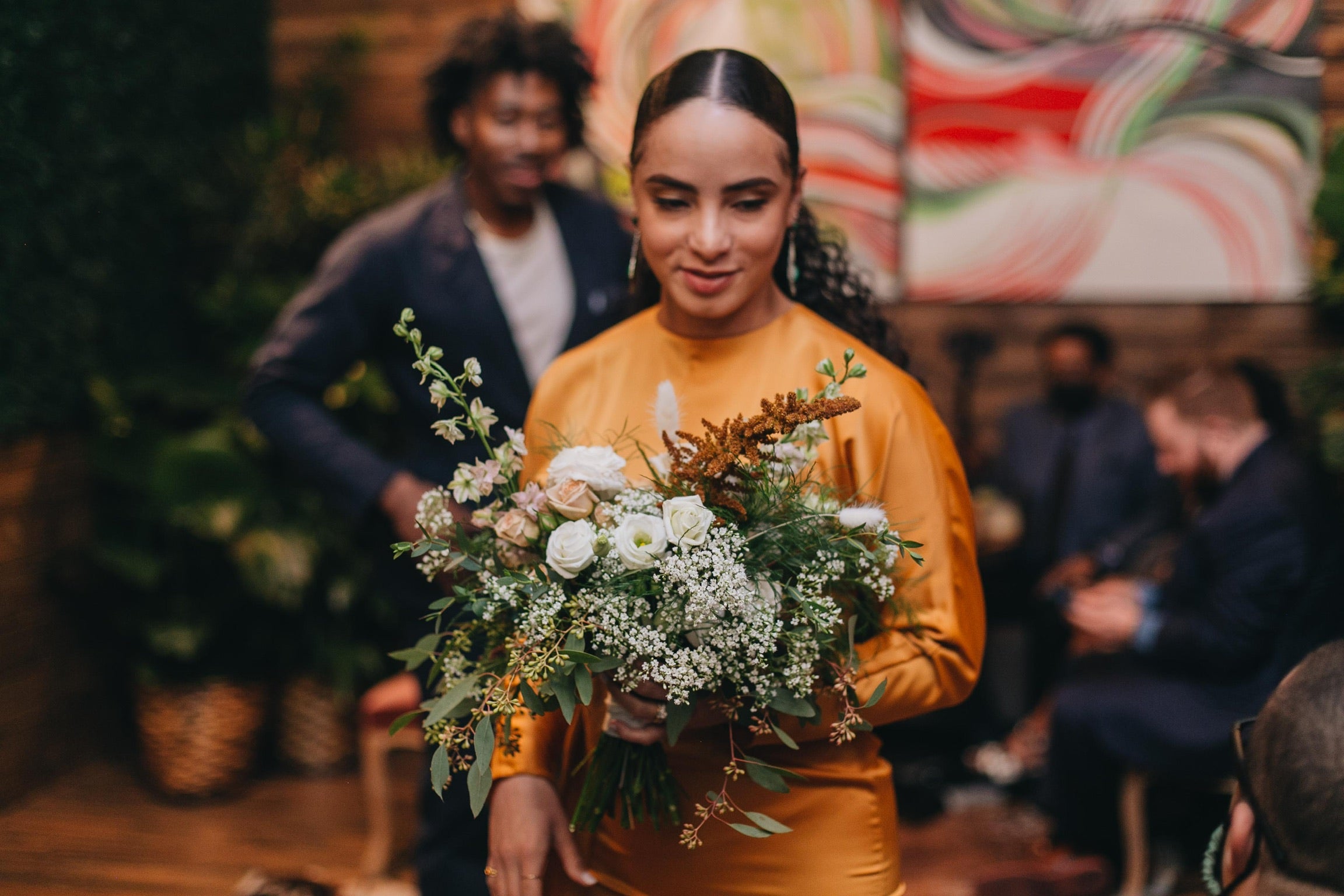 Sprout-home wedding bouquet being held by the bride in terracotta orange. Photograph by Chuck Olu-Alabi