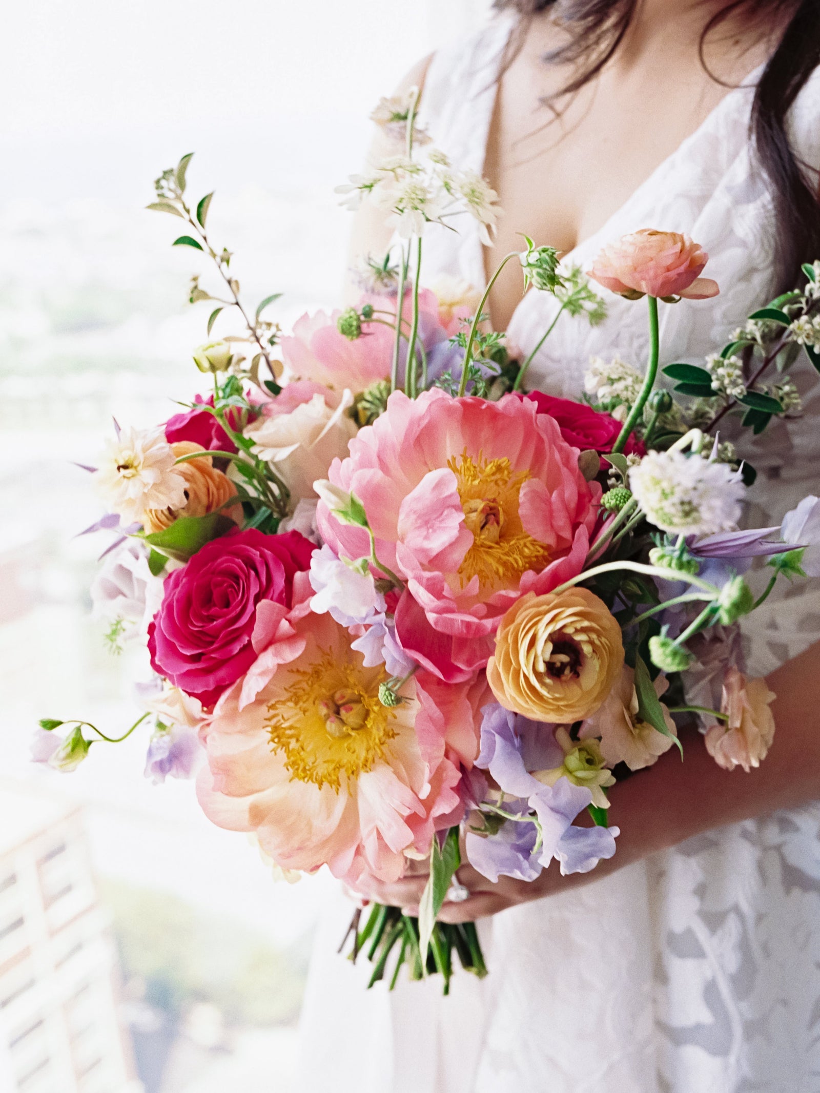 Dominick wedding with the bride holding a bright colorful bridal bouquet featuring peony and ranunculus. Playful and fun bouquet. Floral by Sprout-home. Photograph by Armenteros Weddings