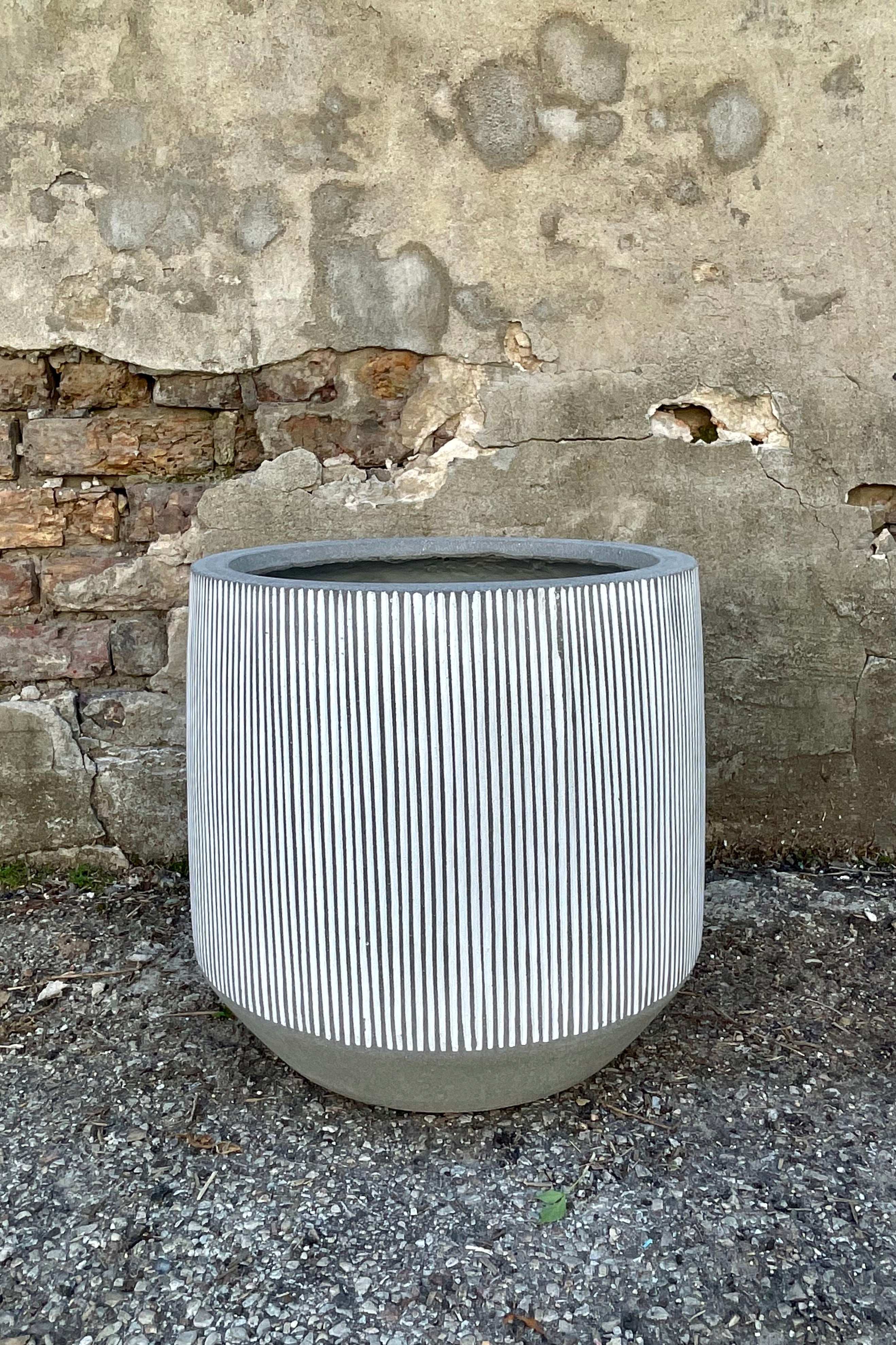 Photo of white and gray striped Harith pot against a cement wall.