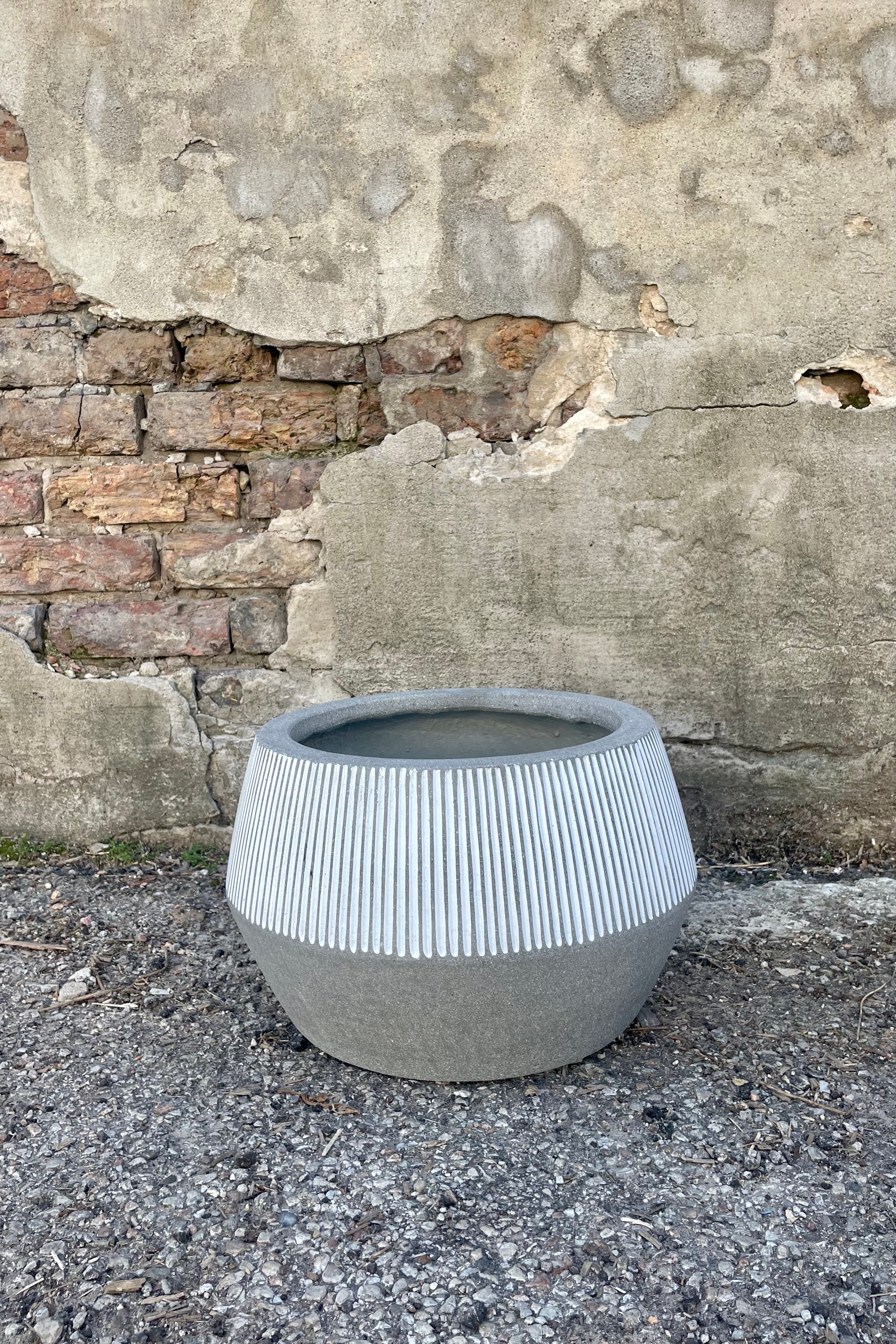 Photo of gray and white striped Harley Low Pot against a cement wall.