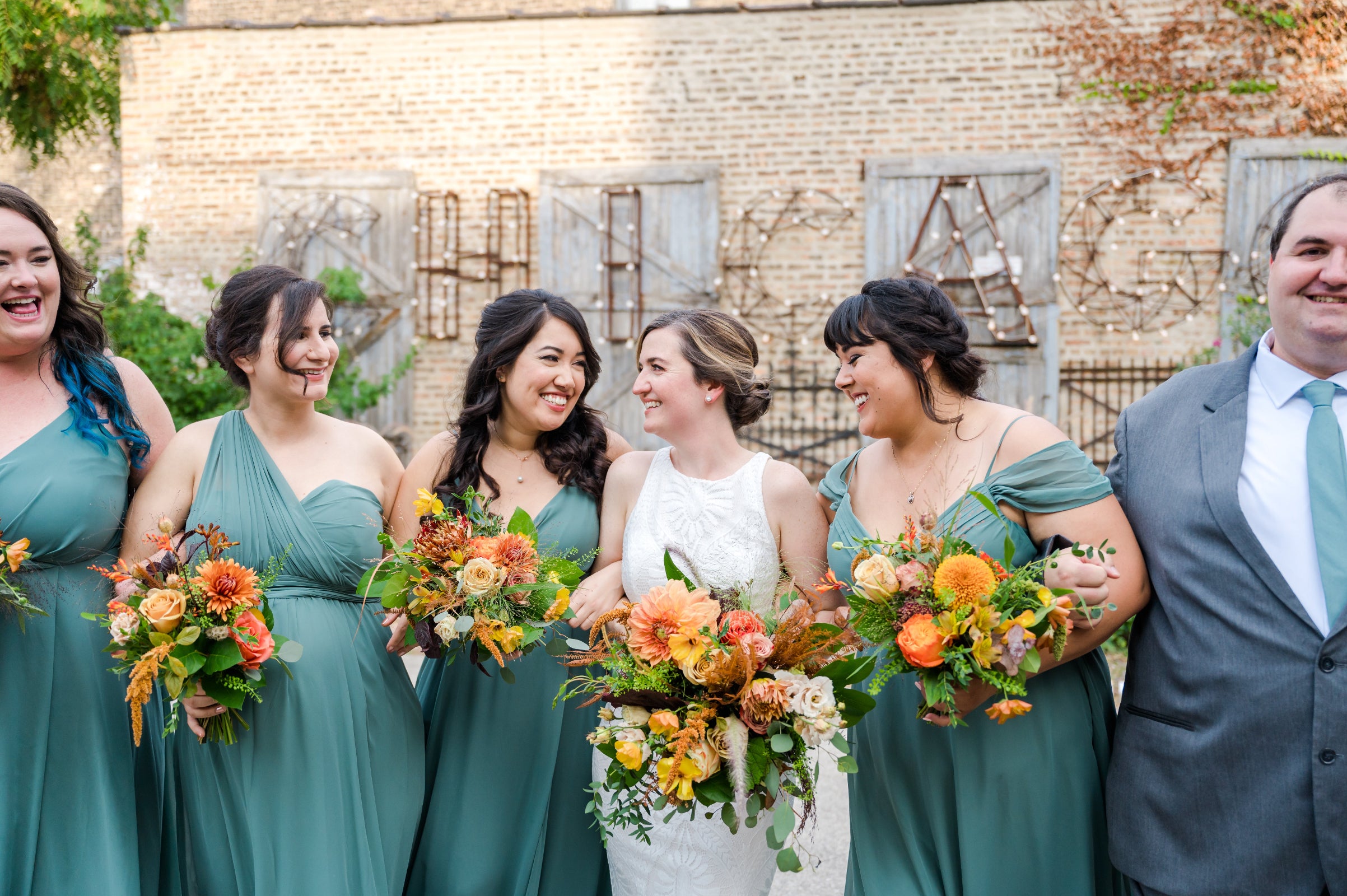 Wedding at Salvage One in Chicago, sage colored dresses for bridesmaids, with bride and all holding floral bouquets by Sprout-home. Photograph by Winterlyn Photography.