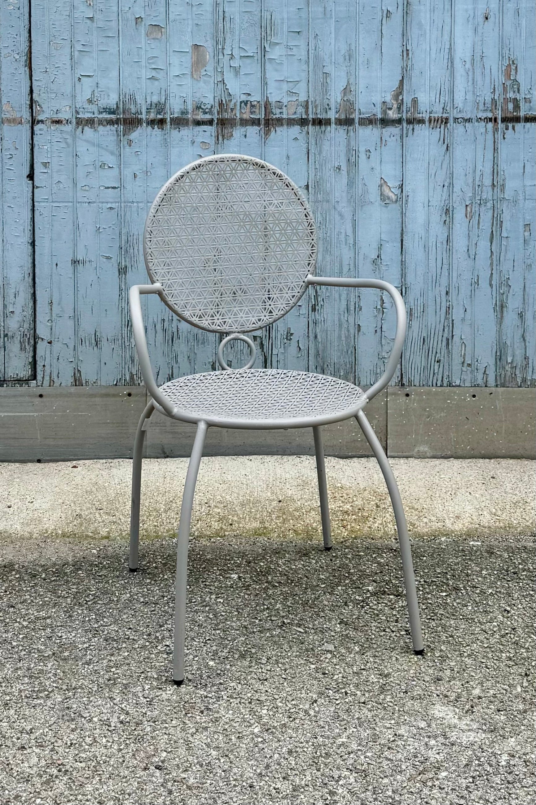 The gray bistro chair at Sprout-home against a blue gray wood wall. 