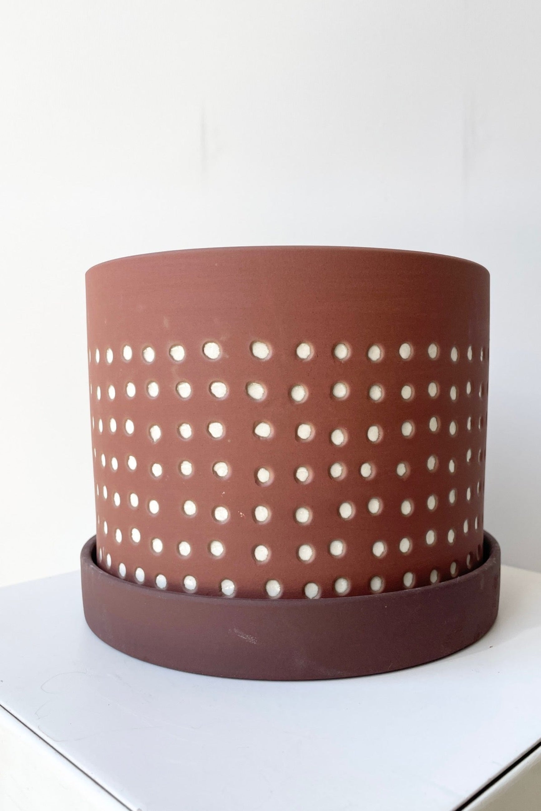 The Salamaca pot and saucer size large showing its brown color with white dots at eye level ©Sprout Home