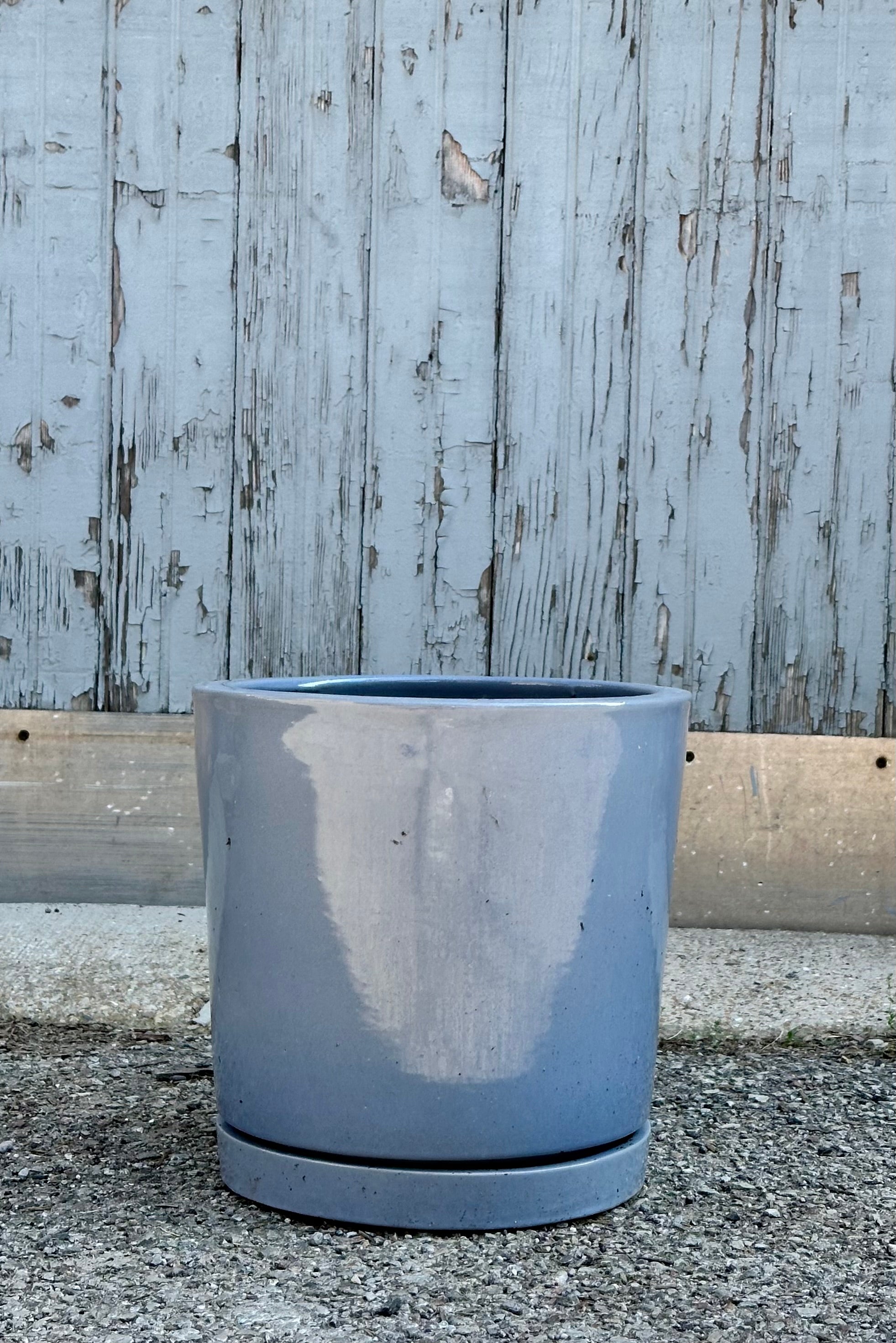 The medium sized Steel Cylinder I/O2 planter viewed from the side against a wood wall. 