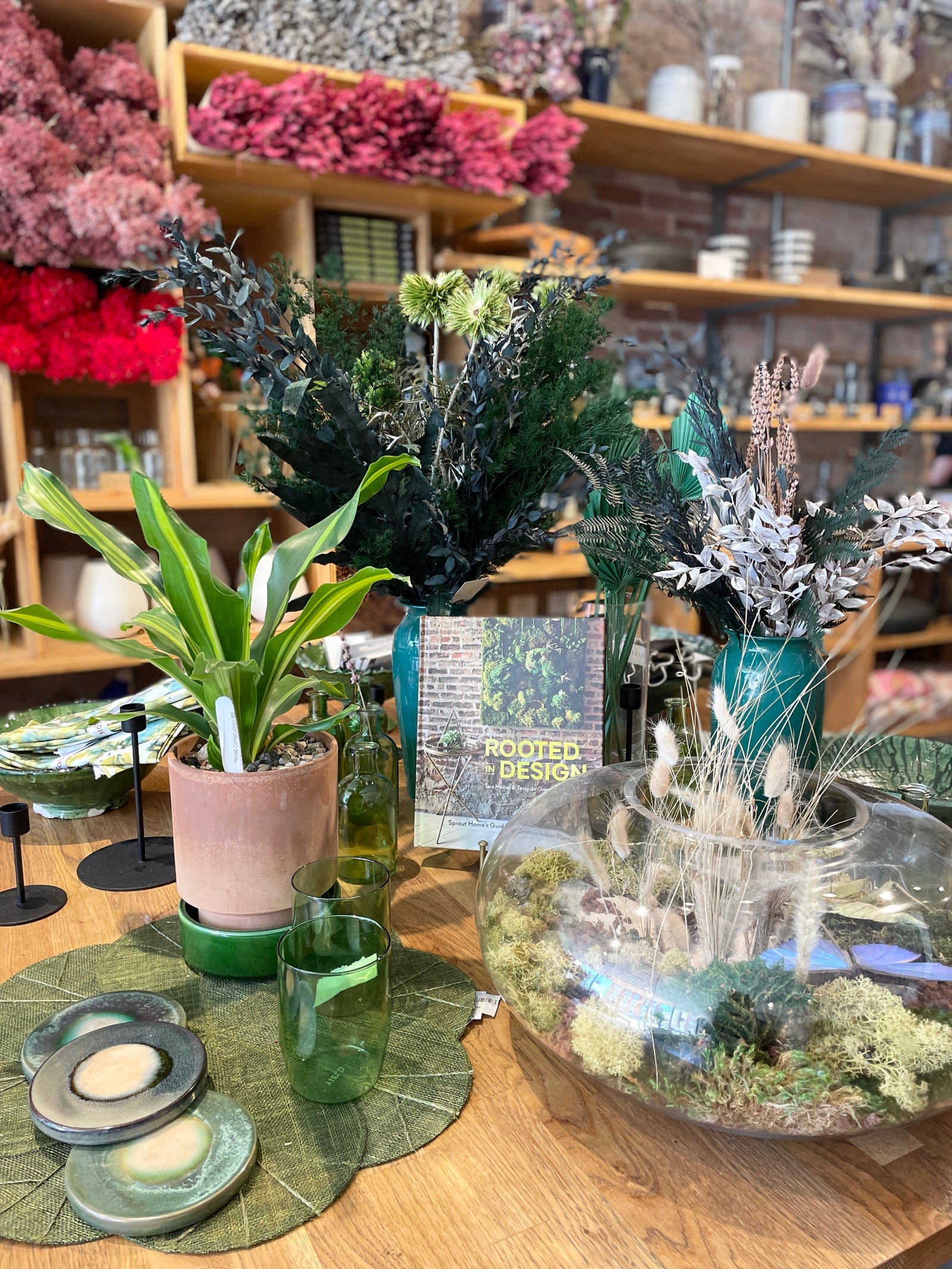 A display table at Sprout-home Floral focusing on green colored home goods, including a terrarium and the Sprout-home book Rooted in Design. 