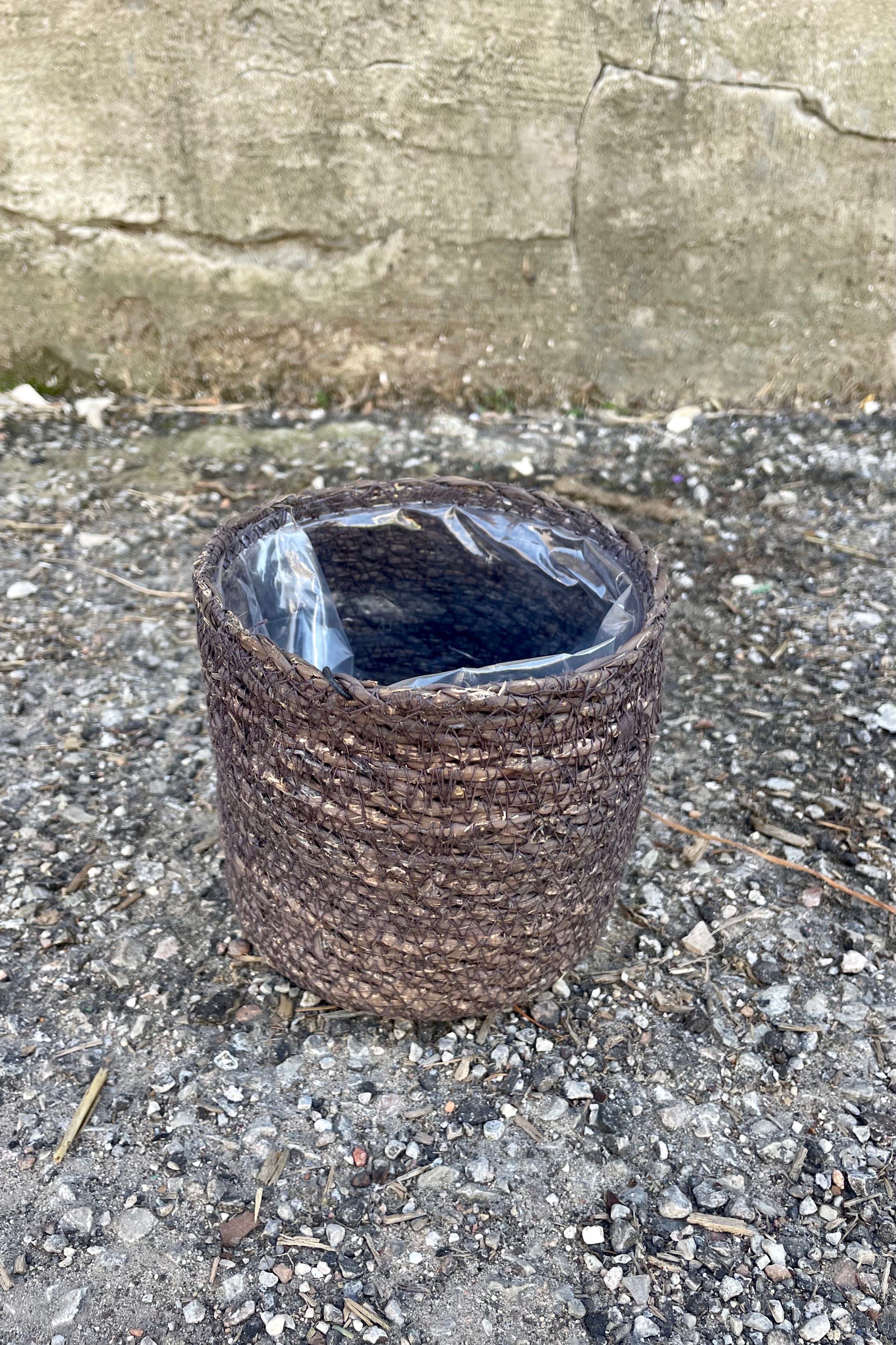 Photo from above of black seagrass basket with liner against a cement wall.