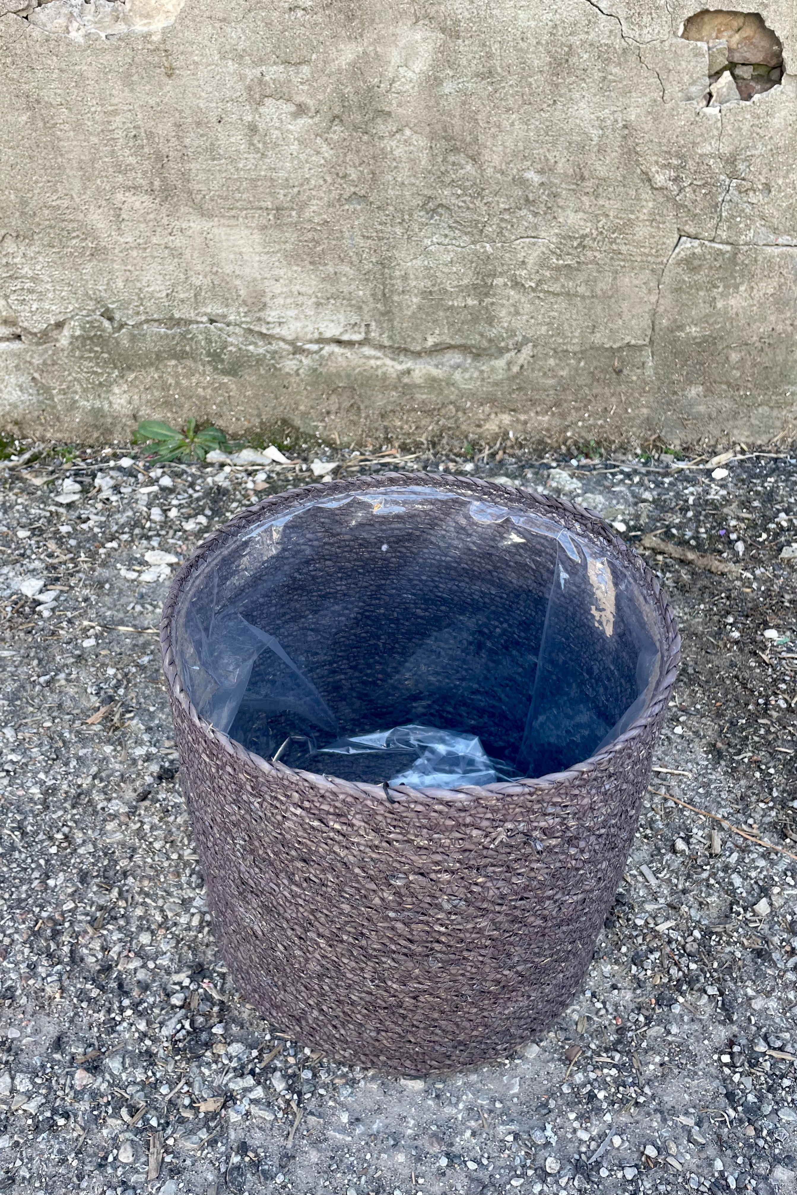 Photo from above of black seagrass basket with liner against a cement wall.