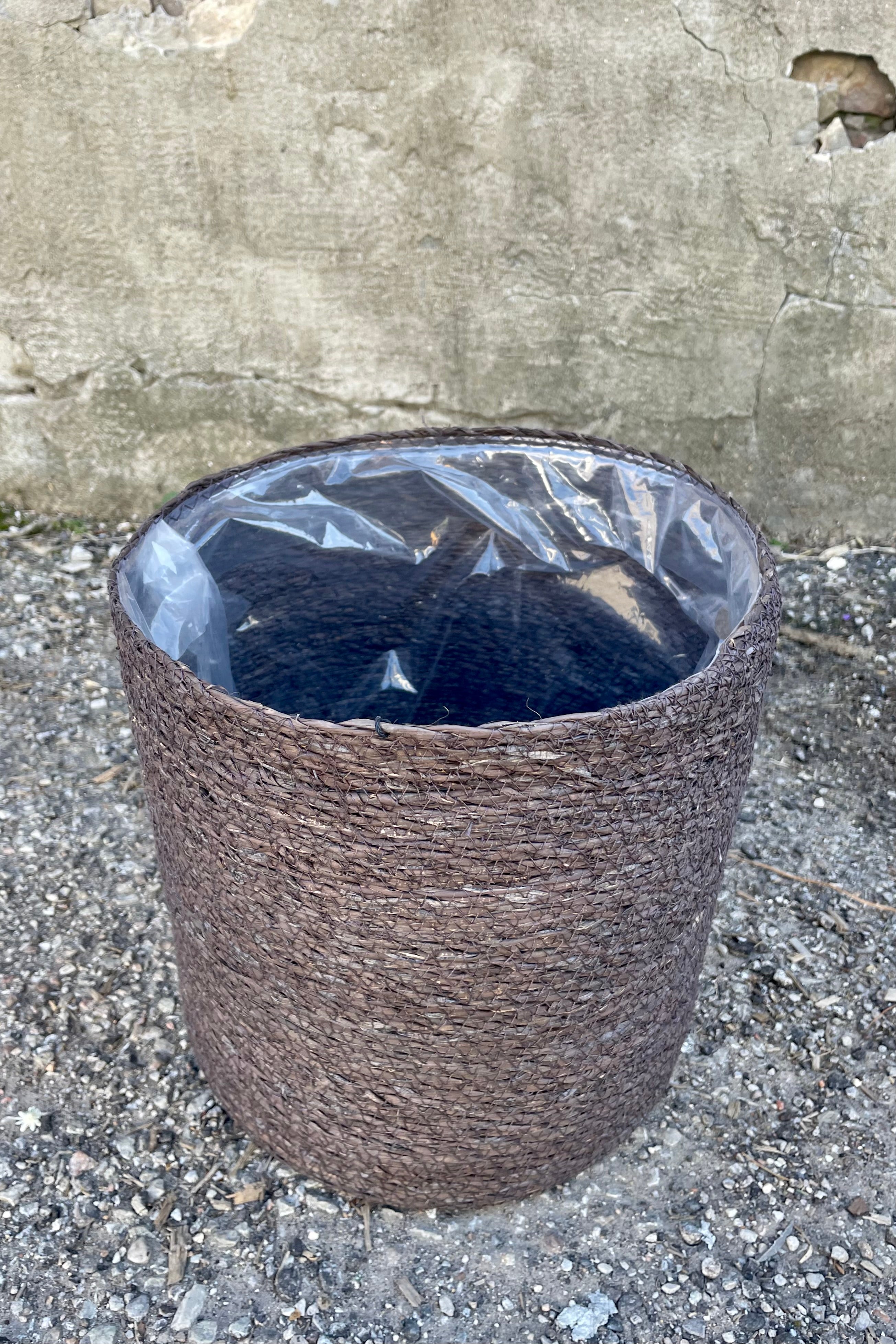 Photo from above of black seagrass basket with liner against a cement wall.