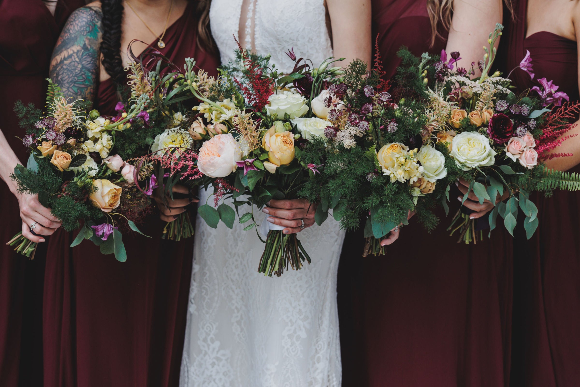 Bridal and bridesmaid bouquets by Sprout-home being held in hand together. Photograph by Angela Renee Photography