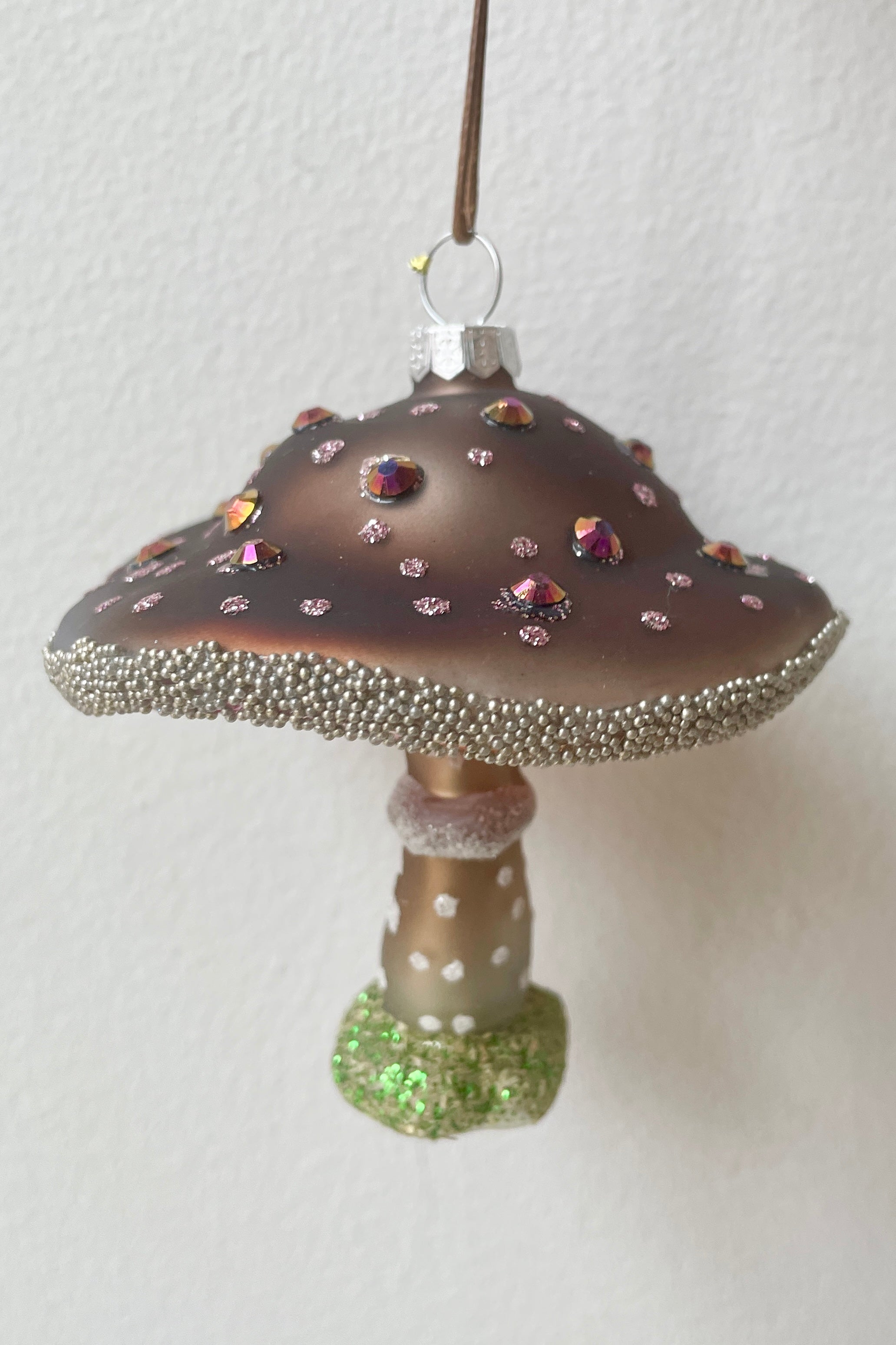 The purple wooded glen mushroom ornament being held against a white wall  available at Sprout-home. 