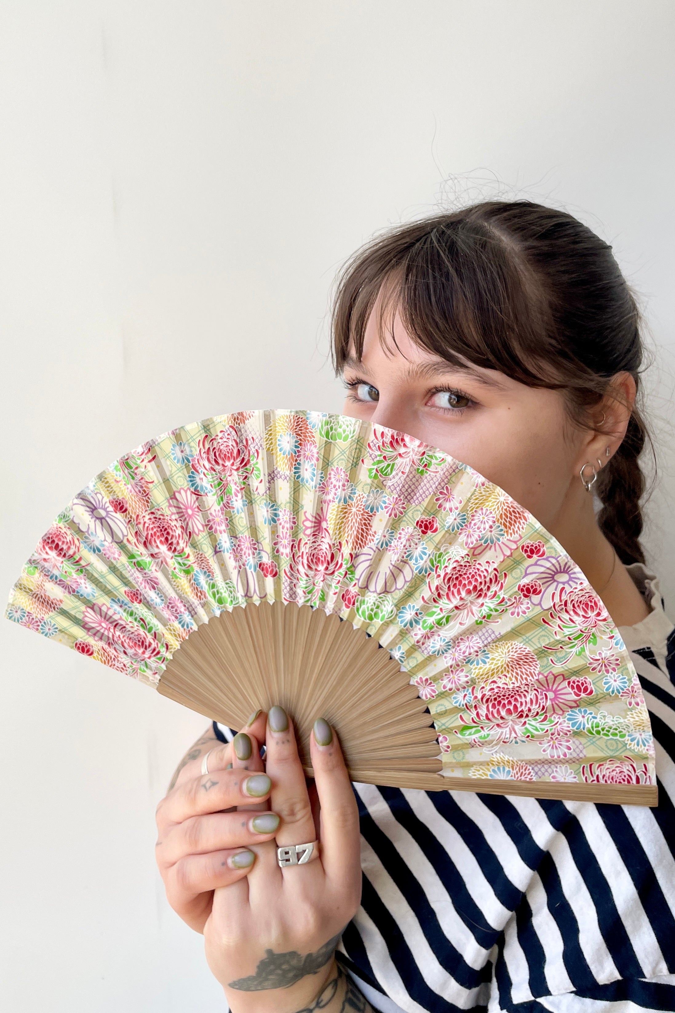 Pale green with Chrysanthemums silk fan being held in hand by a Sprout-home employee. ©Sprout Home