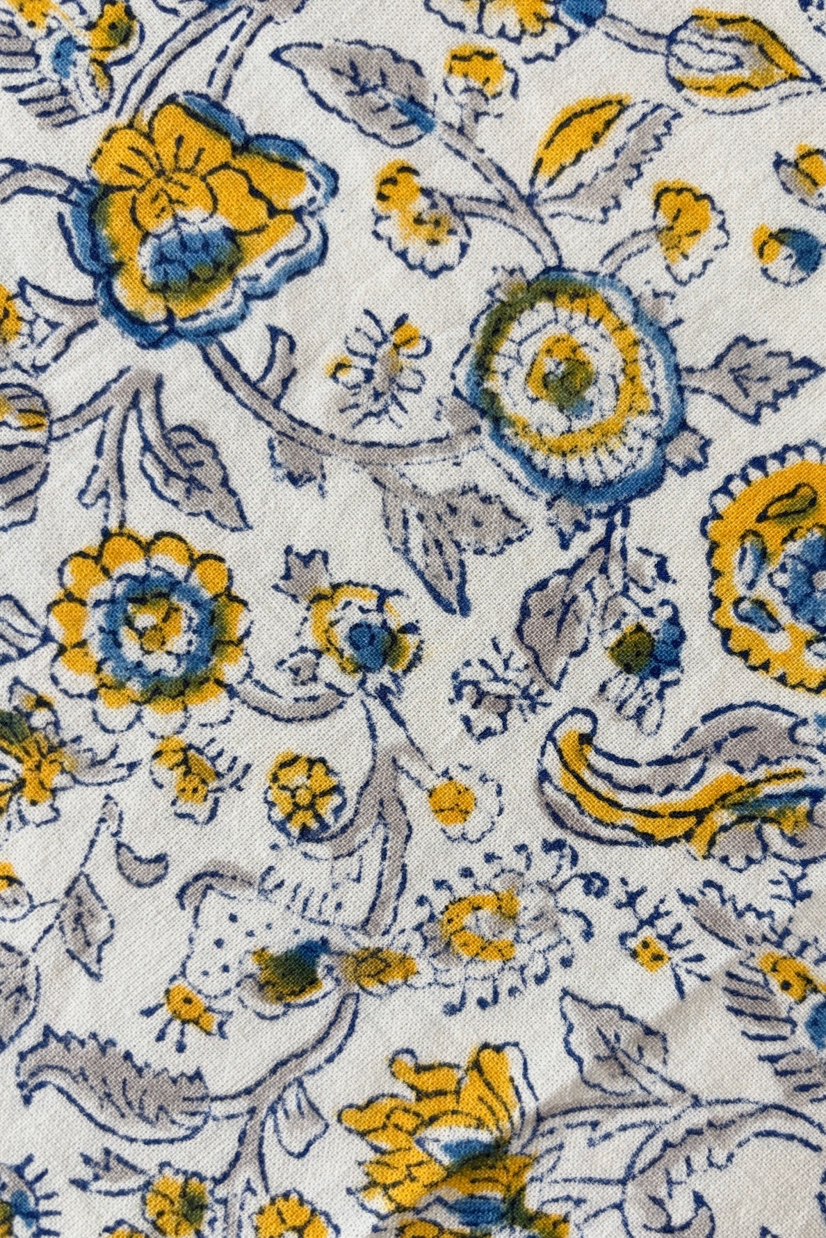 Close up of 100% cotton hand block printed tablecloth with blue and yellow floral motif on white background