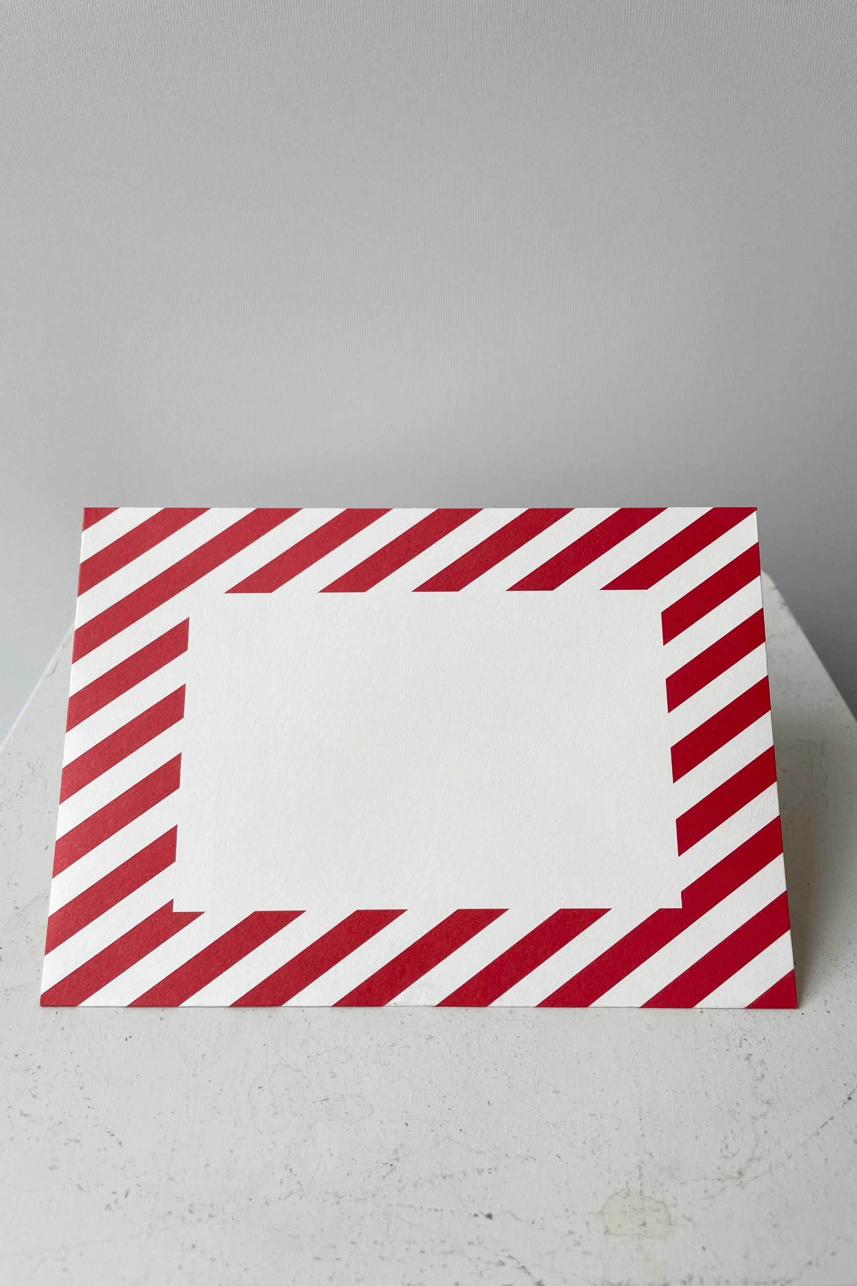 Red and white striped envelope with blank white rectangular on face of envelope.