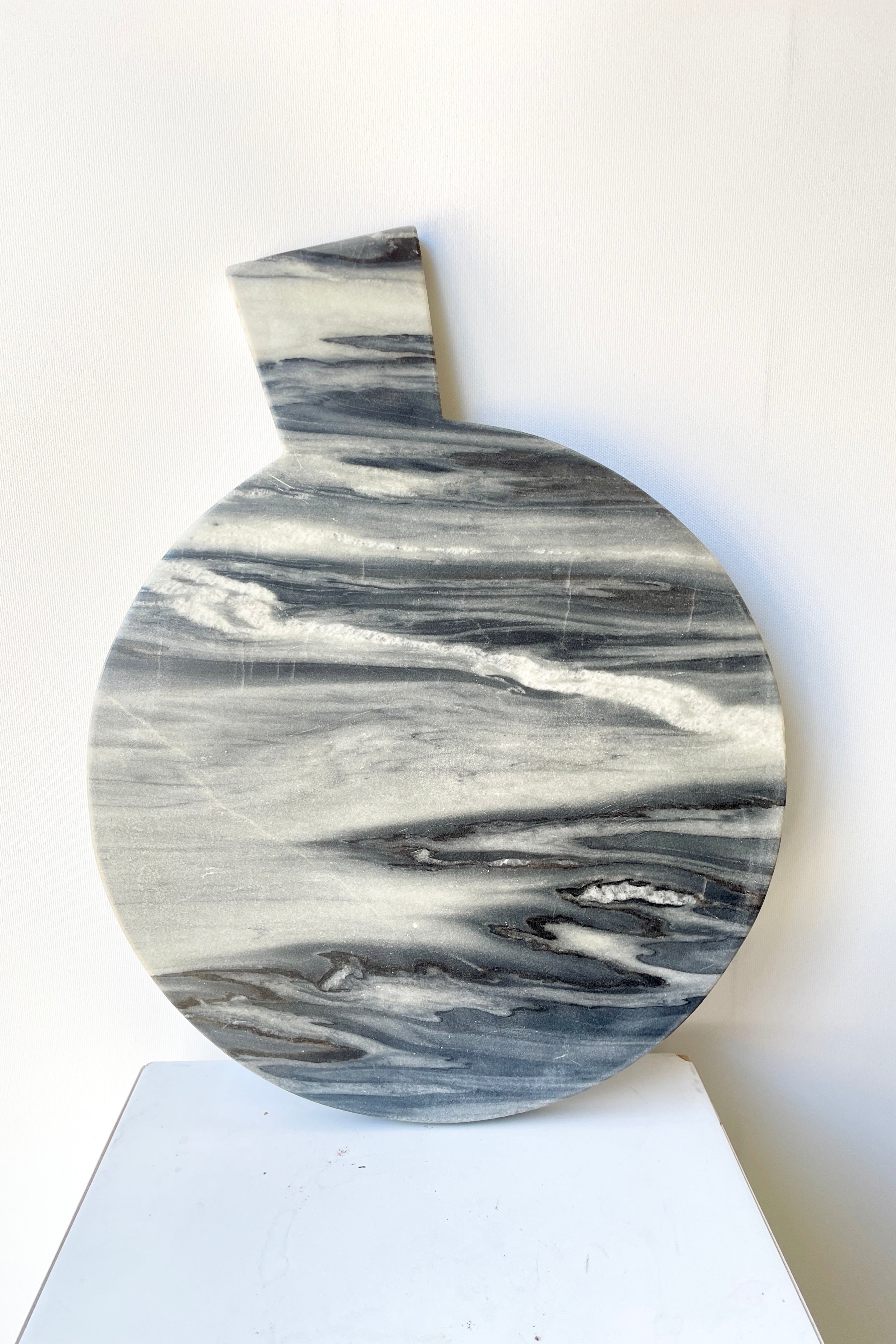 The Black Marble Cheese Board at Sprout-home shown leaning against a white wall. 