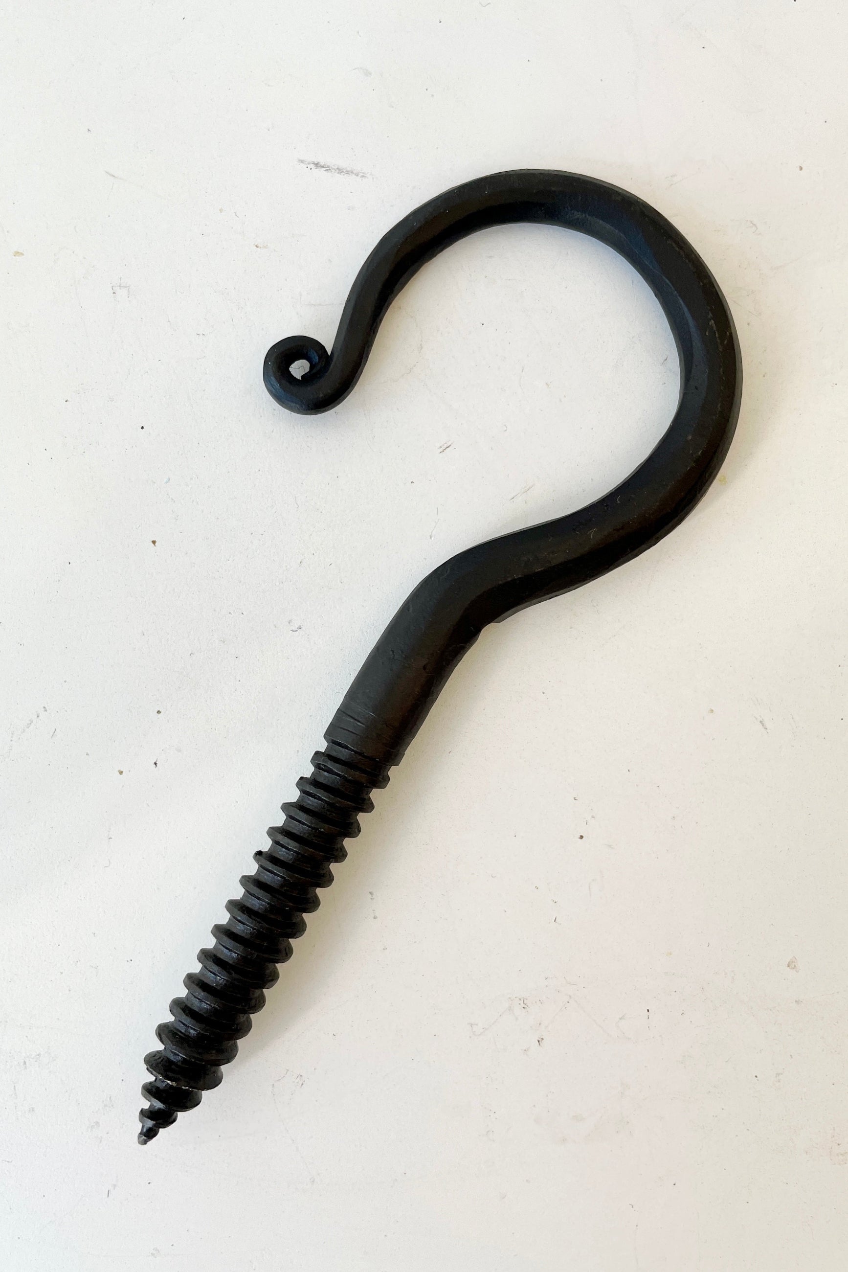 A threaded blacksmiths hook at Sprout-home against a white wall. 