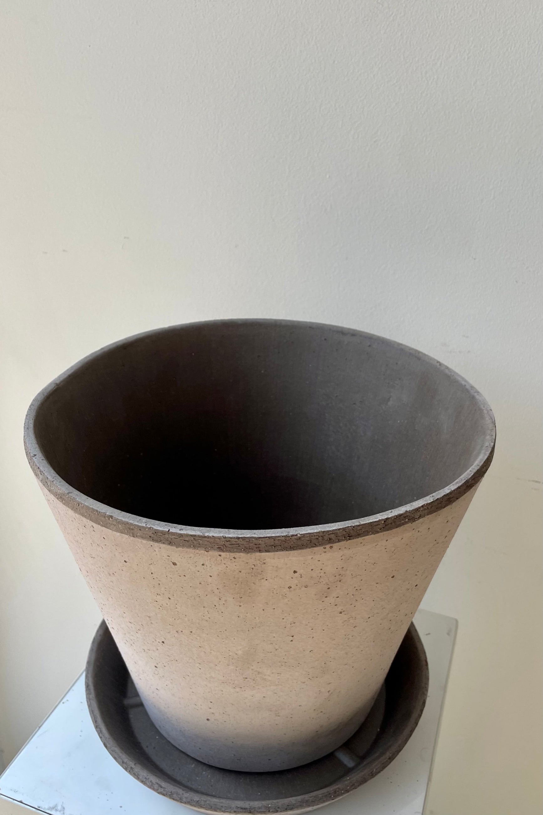 Photo looking down at Julie Pot & Saucer grey 9.8” against a white wall