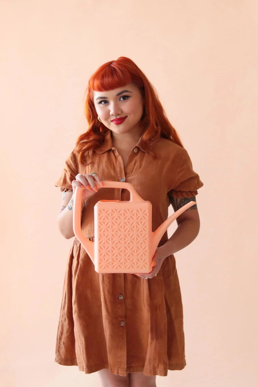 Peach Breeze Block watering can being held in hand by a woman wearing brown by Jungle Club