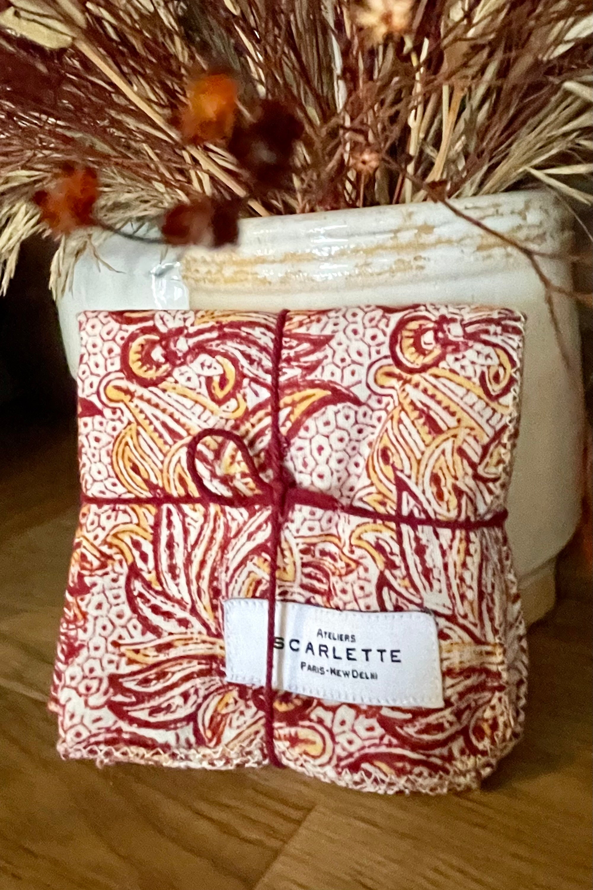 The Acacia napkin set leaning against a white container with dried floral. 