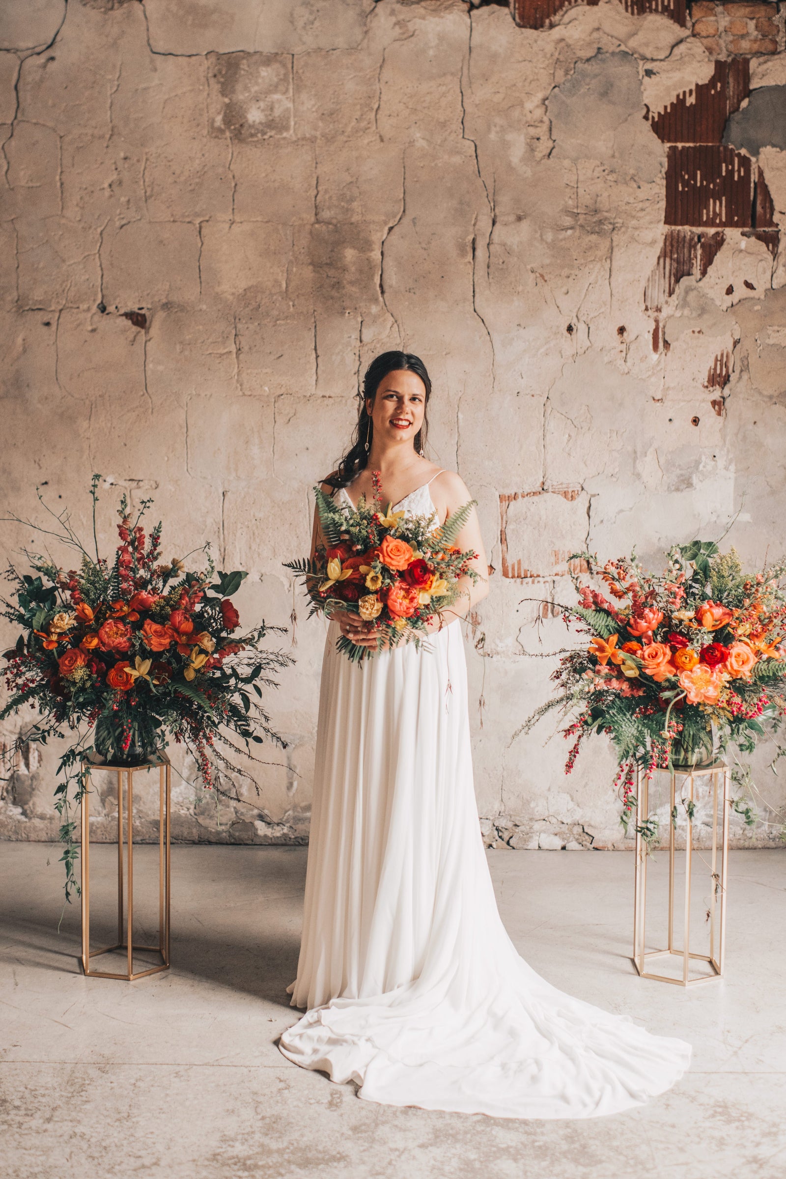 Wedding floral of warm reds and oranges with two larger alter arrangements and the bride with a bridal bouquet a the Charcoal Loft in Chicago. floral designed by Sprout-home.  Photography by Julia Marumaya Photography. 