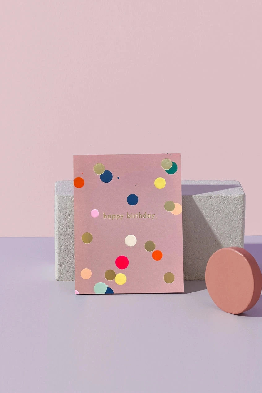 MOglea Happy Birthday Dots Card sitting on a purple surface against a concrete brick. 
