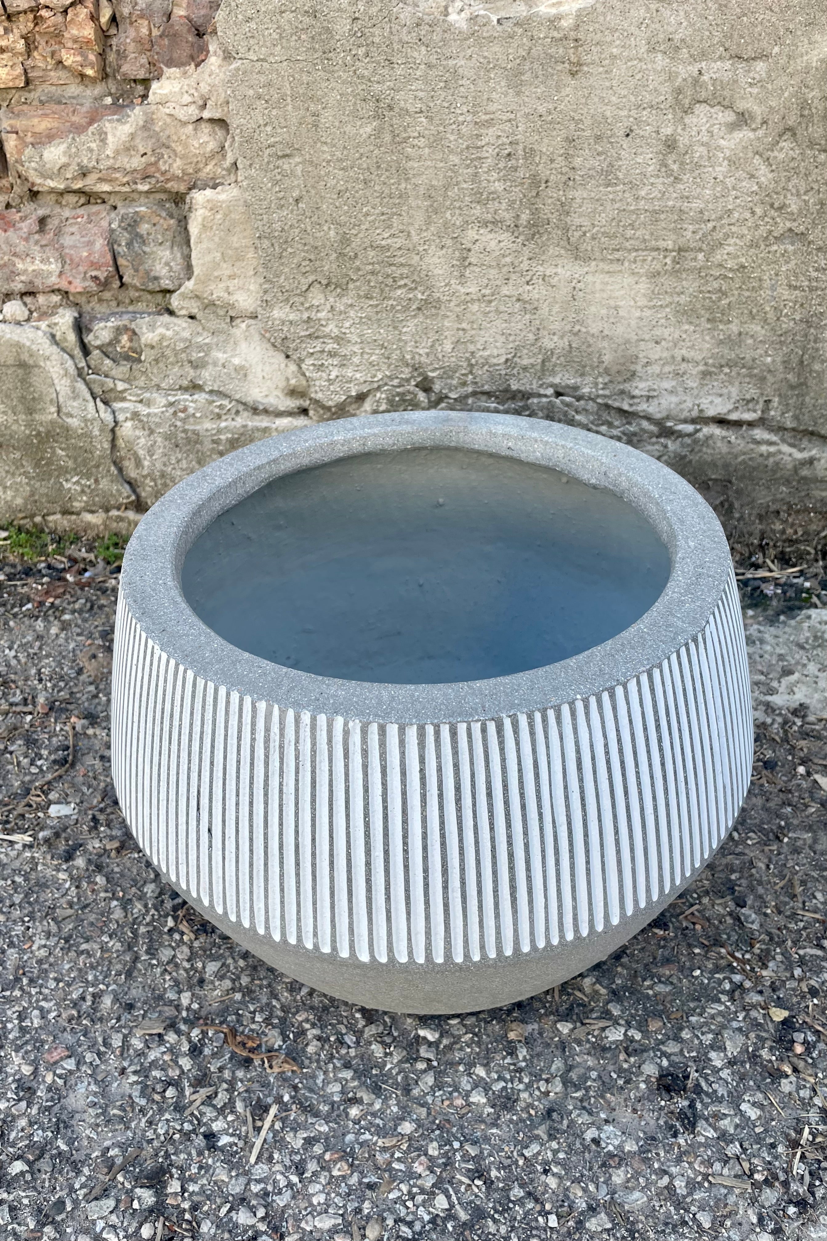 Photo from above of a gray and white striped Harley Low Pot against a cement wall. 