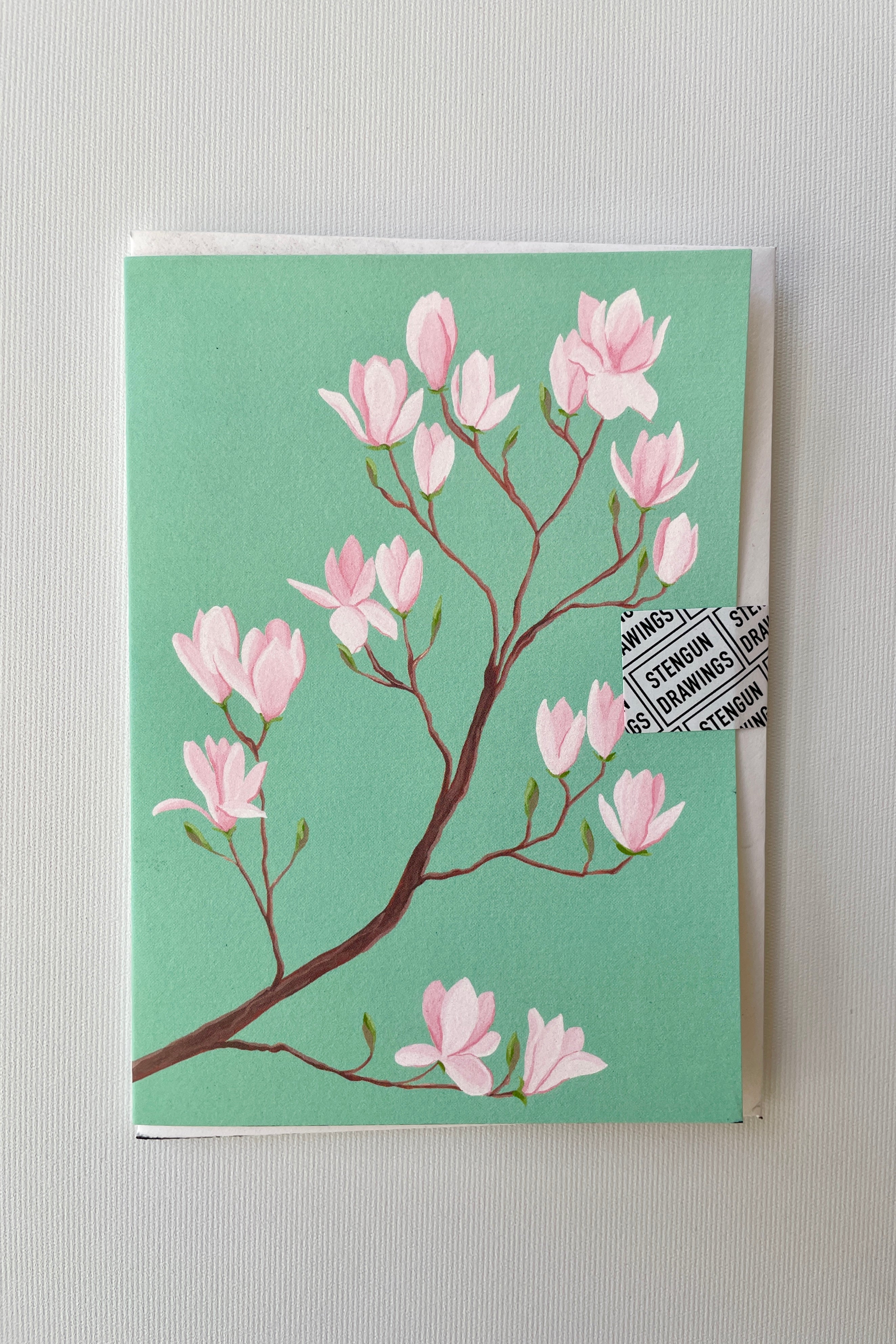 A Magnolia greeting card by Stengun at Sprout-home with its turquoise background and pink flowers. 