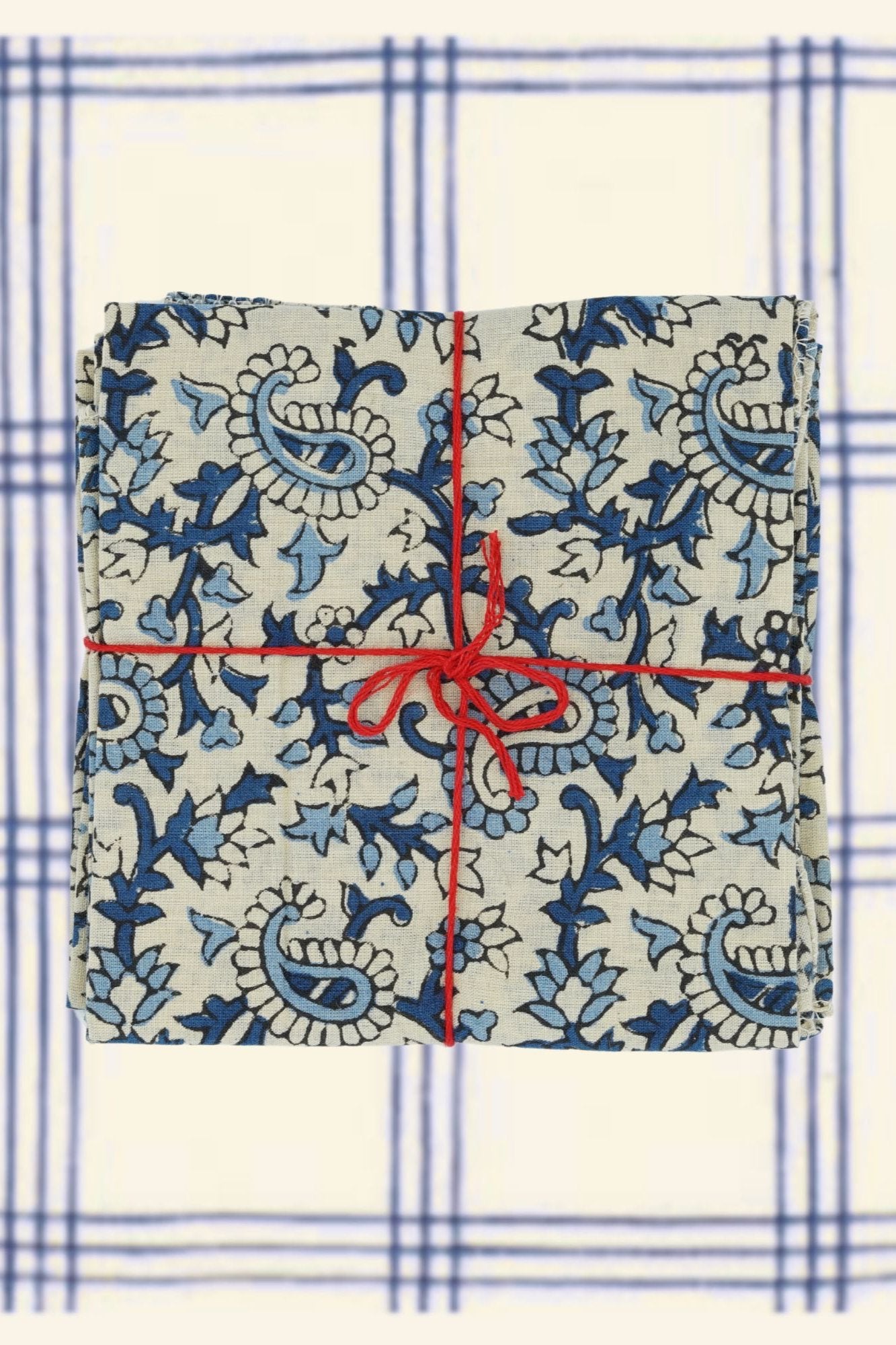 Suzette Cotton Napkins Pourpier Cobalt tied with a red string on a blue and white checked linen.