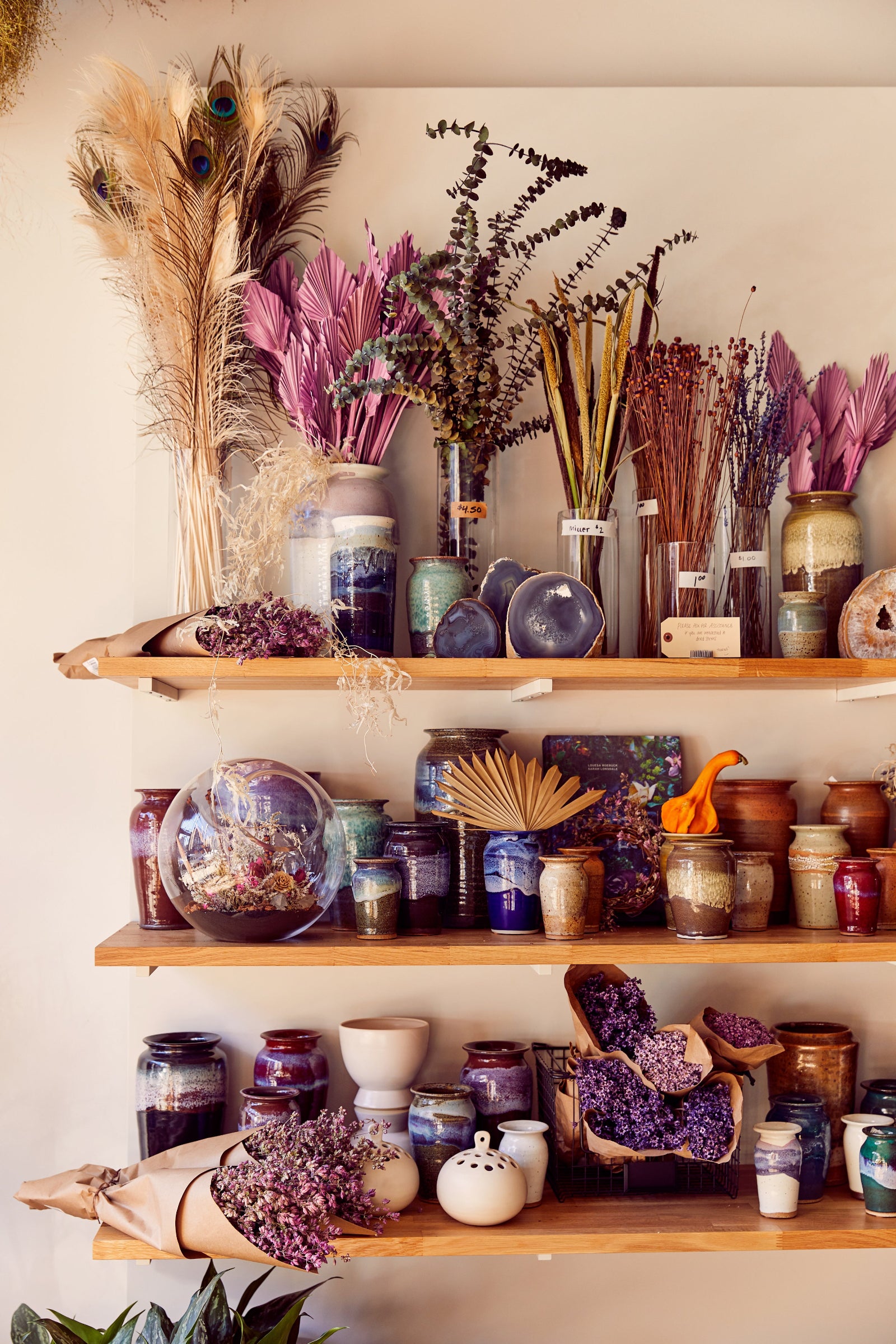 Shades of purple, magenta and brown homeware and dried floral on shelves at Sprout-home Floral in Chicago