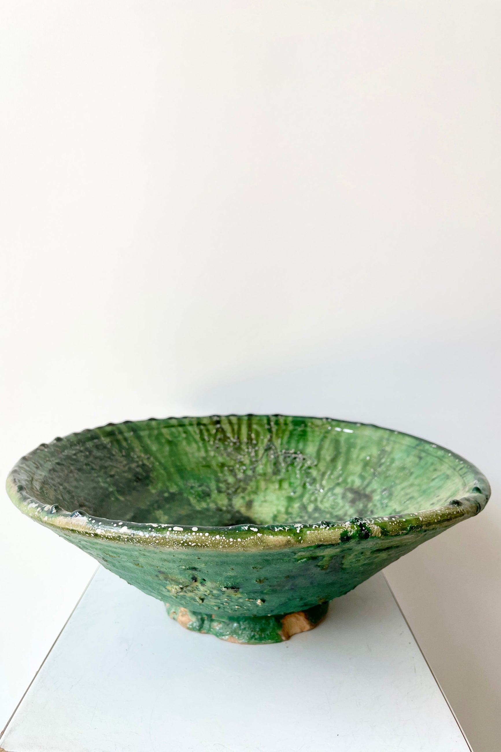 The large tamaegroute green bowl at Sprout-home shown from the side against a white wall. 