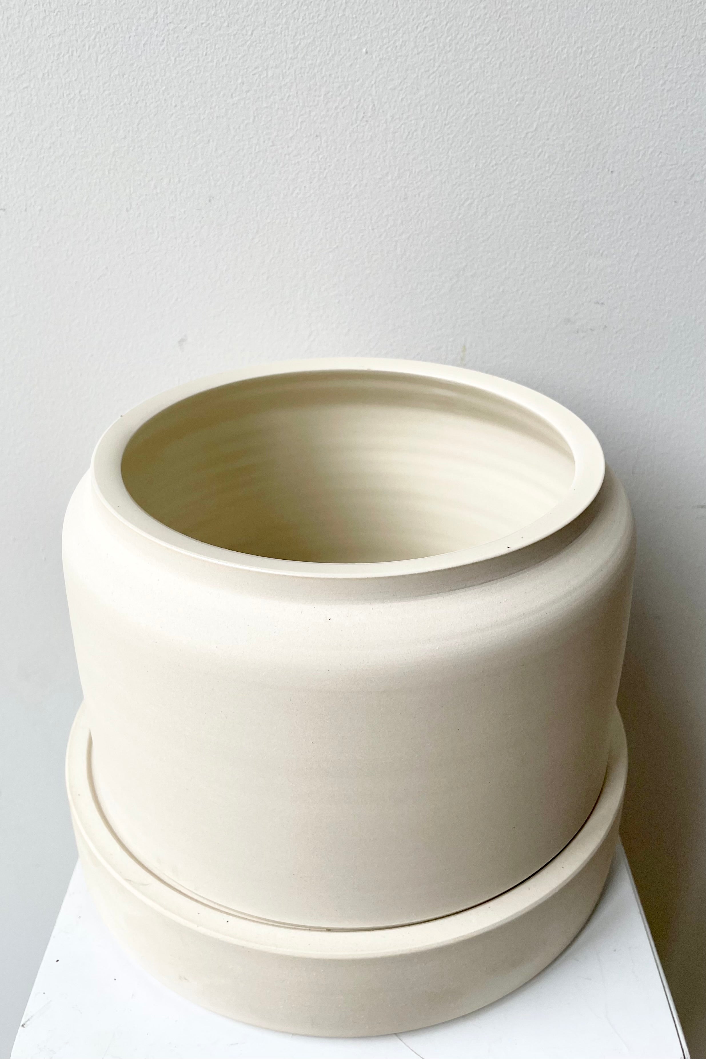 The wide white self watering planter pictured from above and the side. 