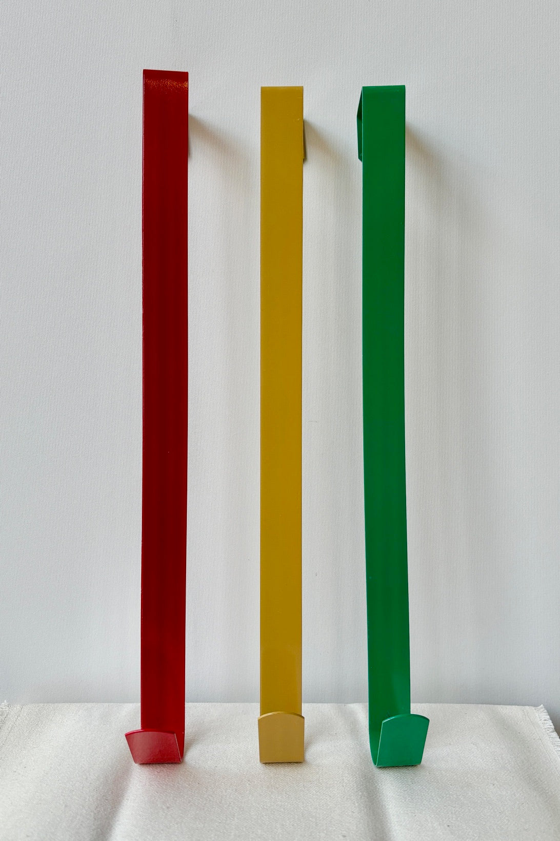 Simple wreath hanger in red, gold and green against a white wall ©Sprout Home
