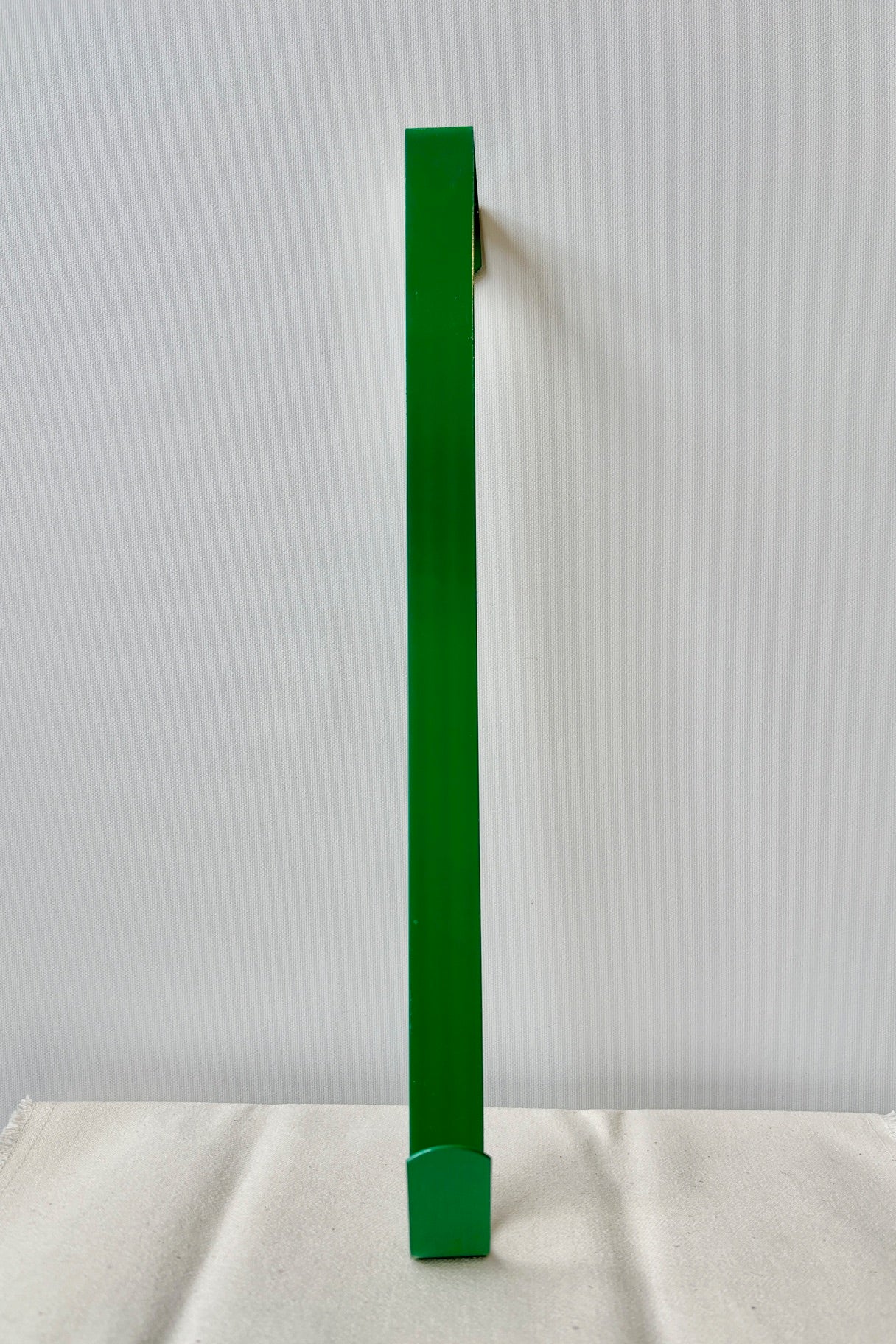 Simple wreath hanger in green against a white wall ©Sprout Home