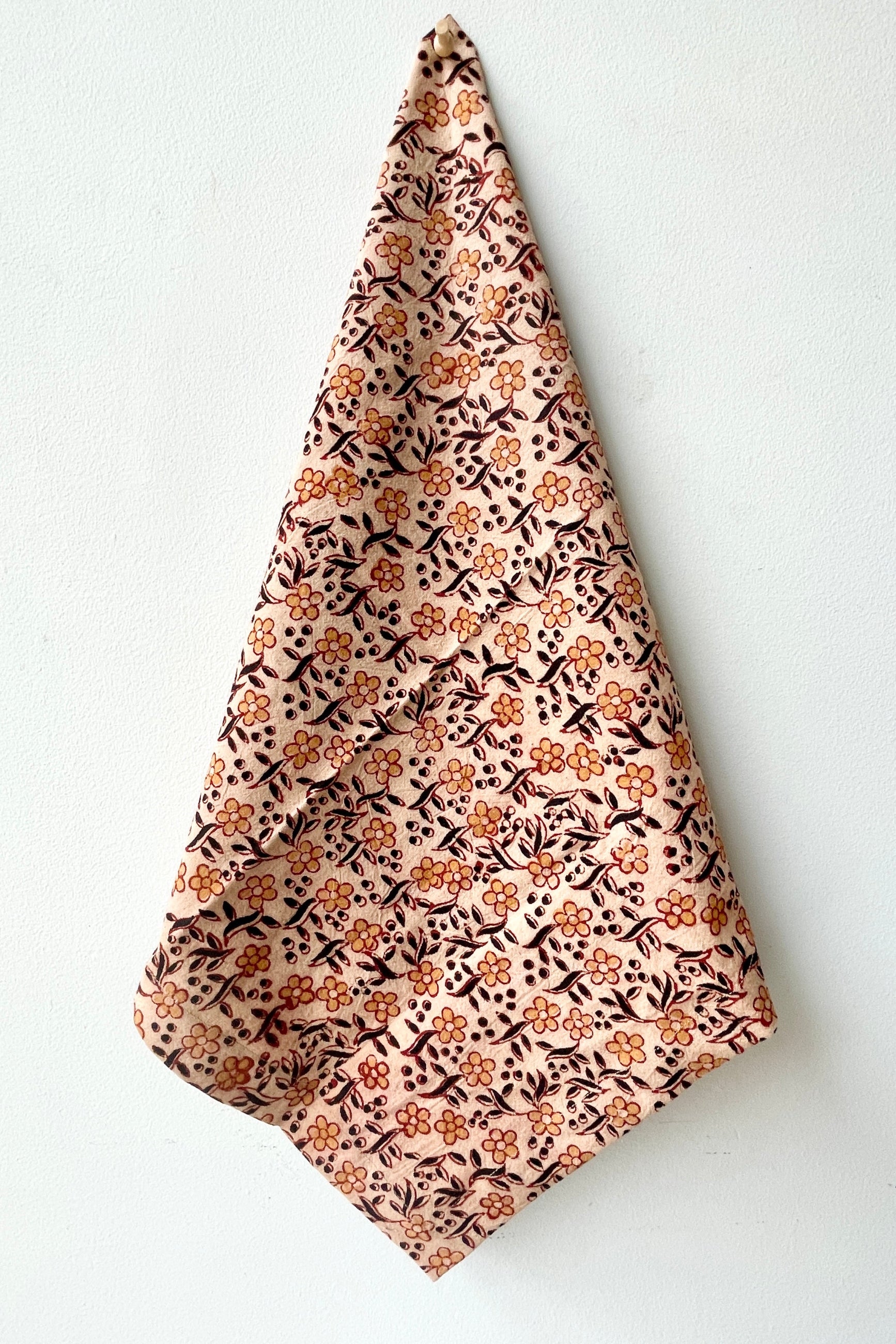 The Sao Anika napkin being held against a white wall. 