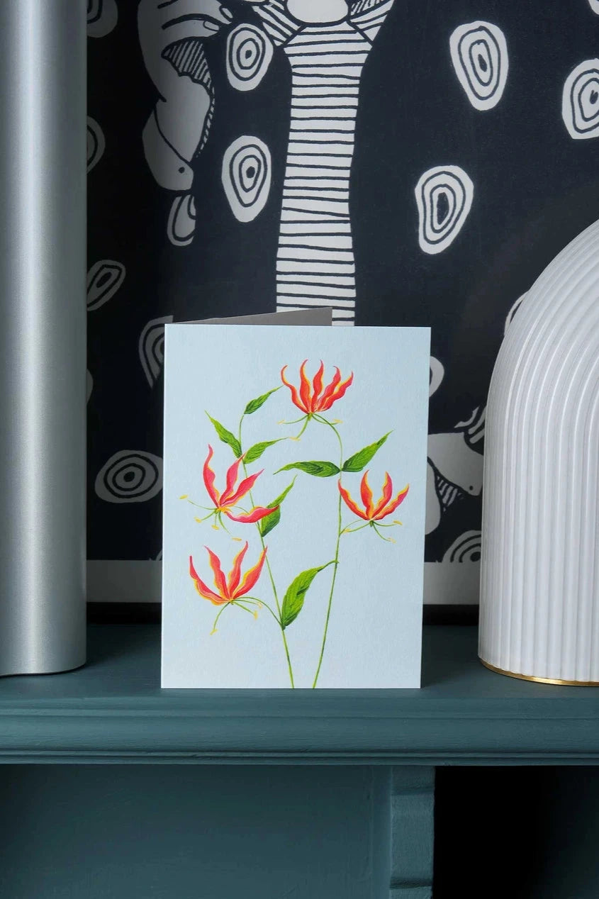 Flame Lily card by Stengun Drawings in a lifestyle shot with the card sitting upright on a ledge. 