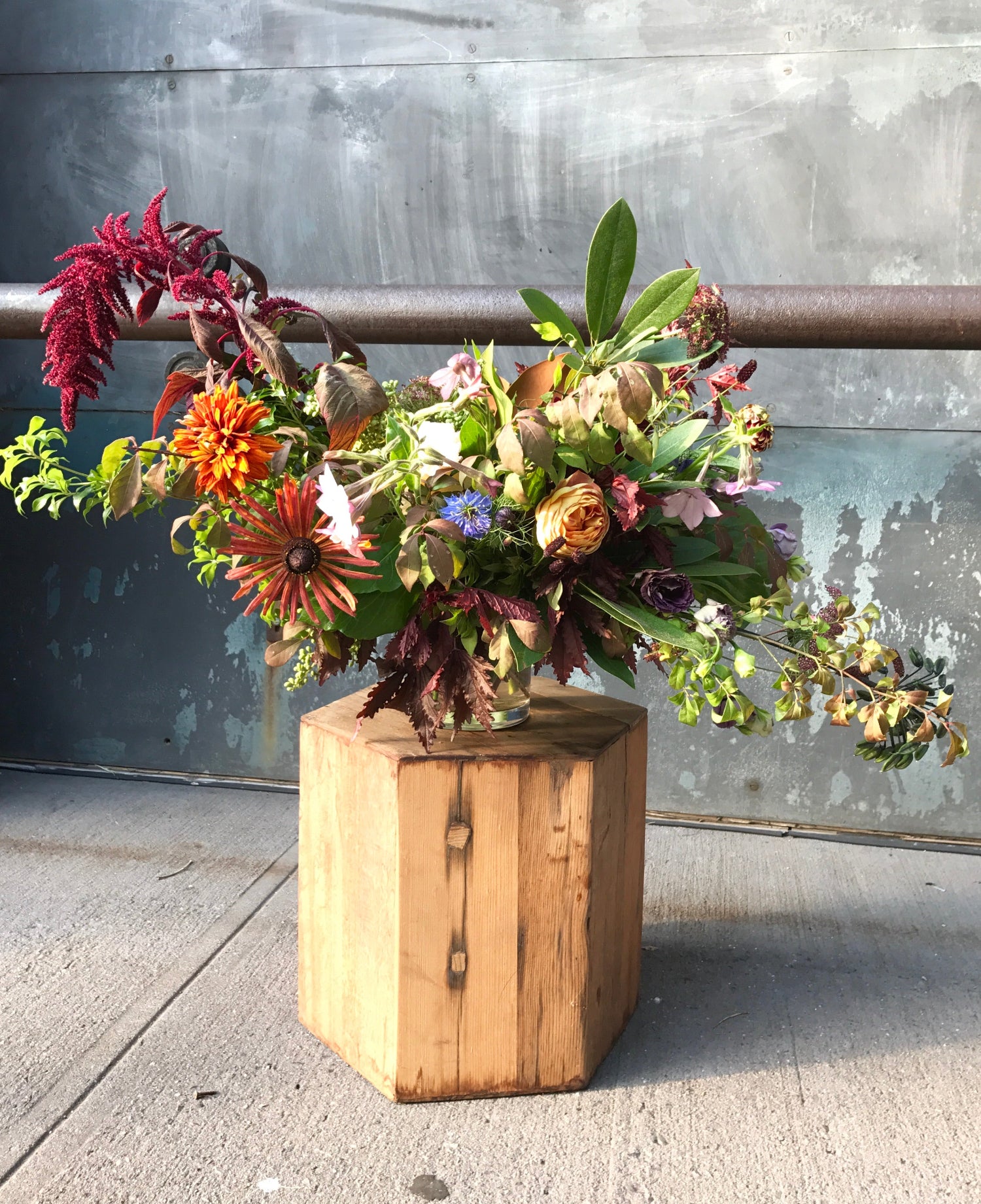 A large Fall season arrangement featuring amaranthus and rudbeckia by Sprout-home. sitting on a wood pedestal.  Photo by Sprout-home. 