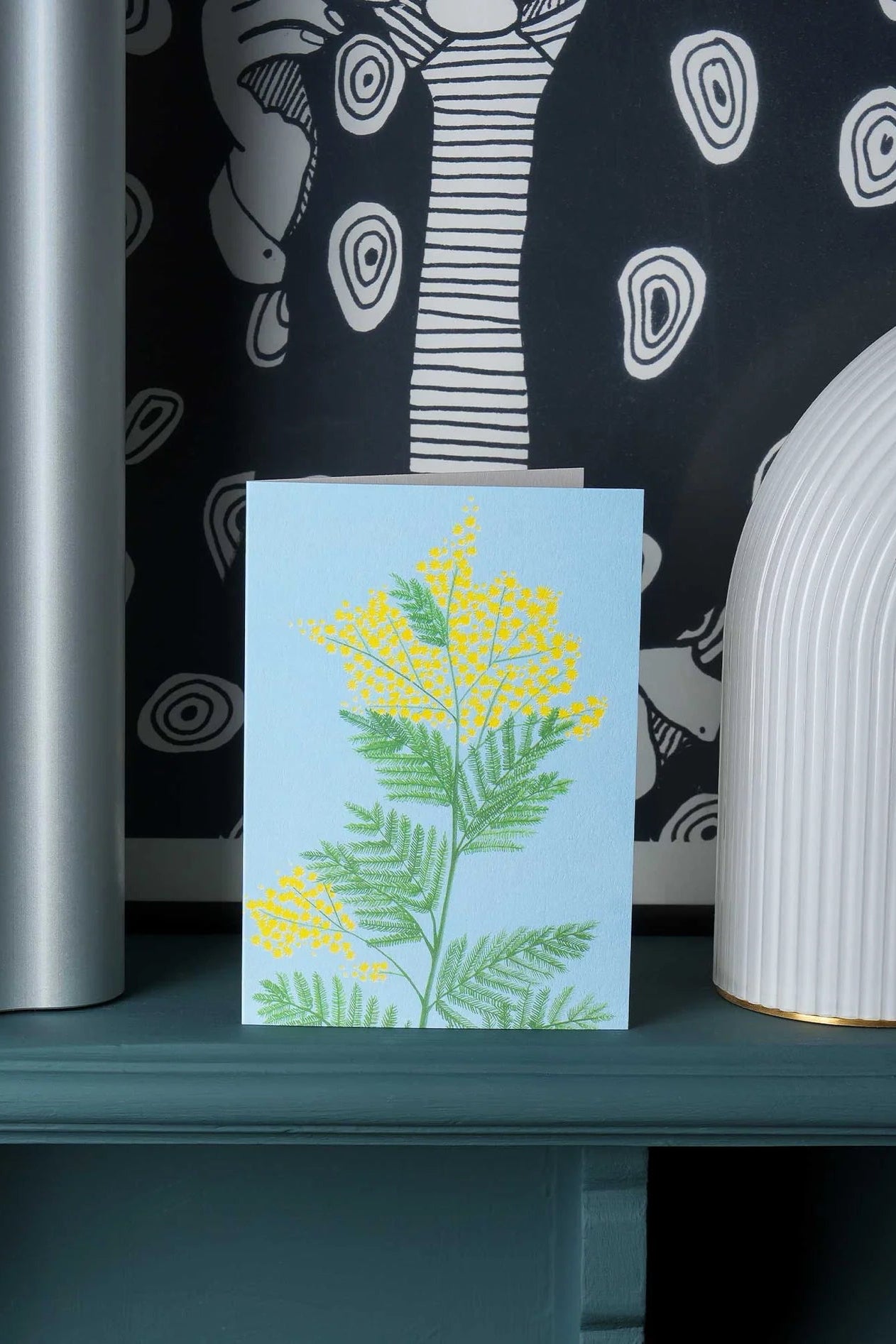 Mimosa Greeting Card sitting on a shelf in front of black and white wallpaper ©Stengun Drawings