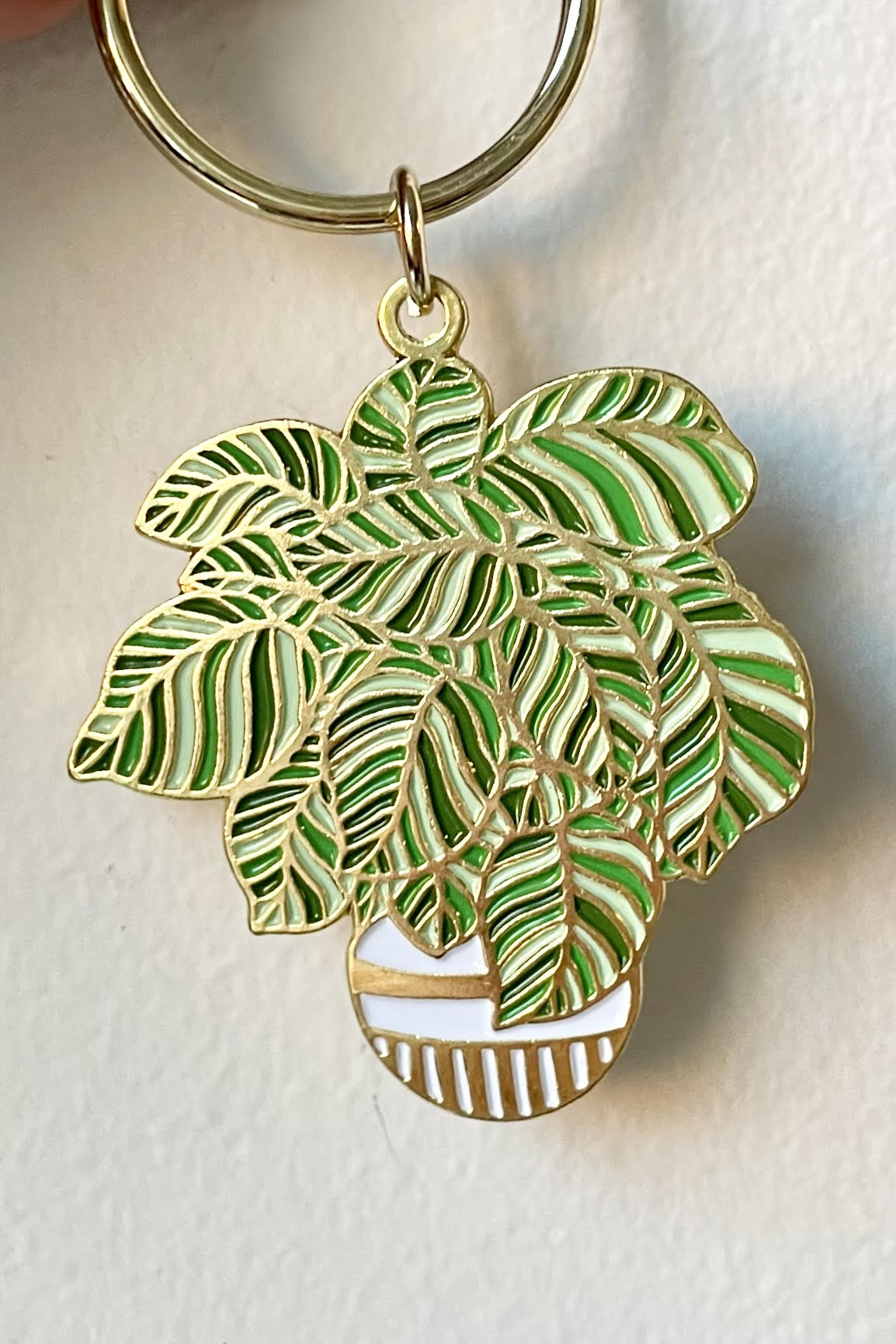 The Plant keychain is held against a white backdrop.