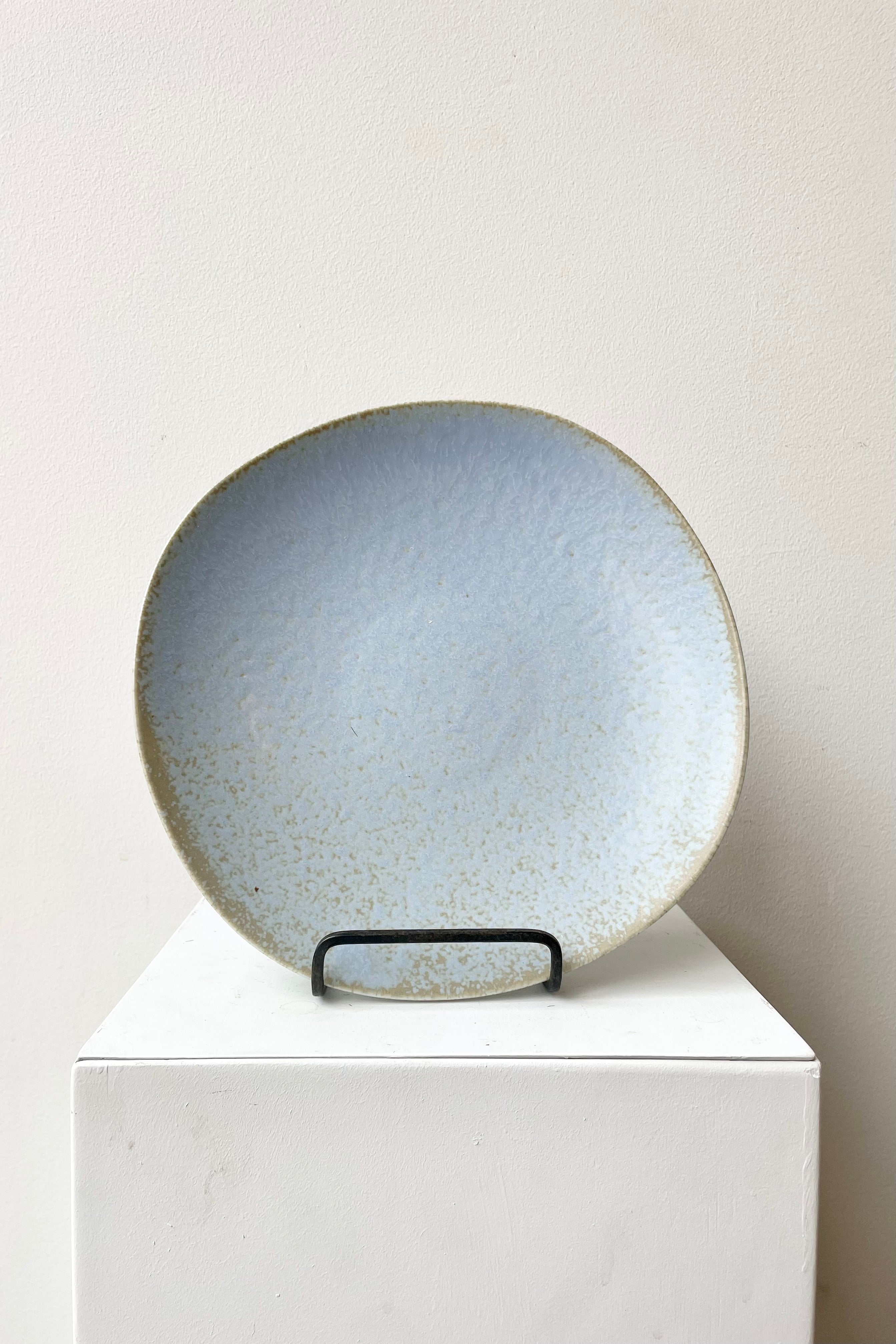 The Shiho dinner plate in grey shown from above against a white wall. 