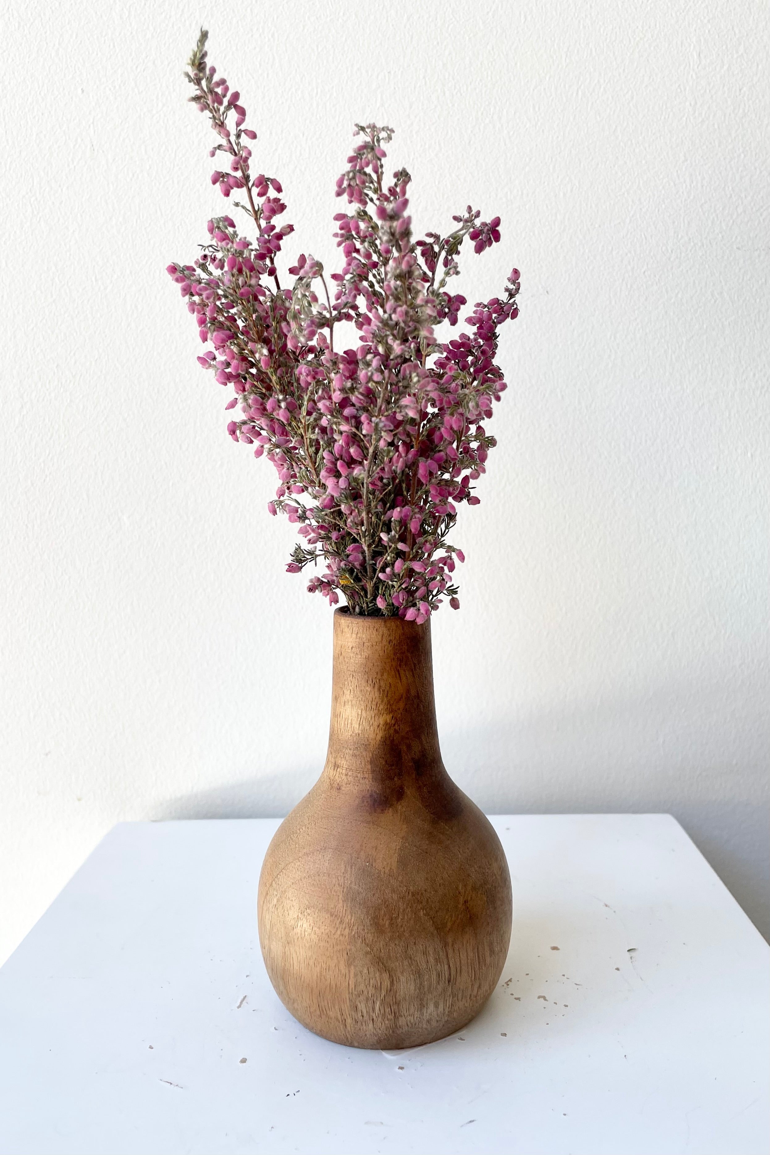 The Nina walnut wood vase large with dried floral against a white wall at Sprout-home. 