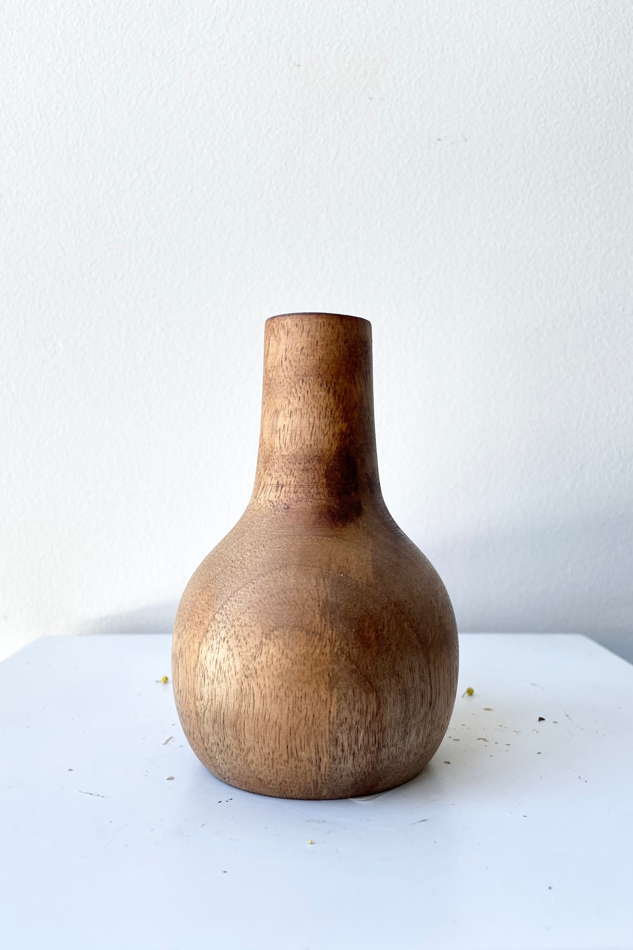 The Nina walnut wood vase large against a white wall at Sprout-home. 