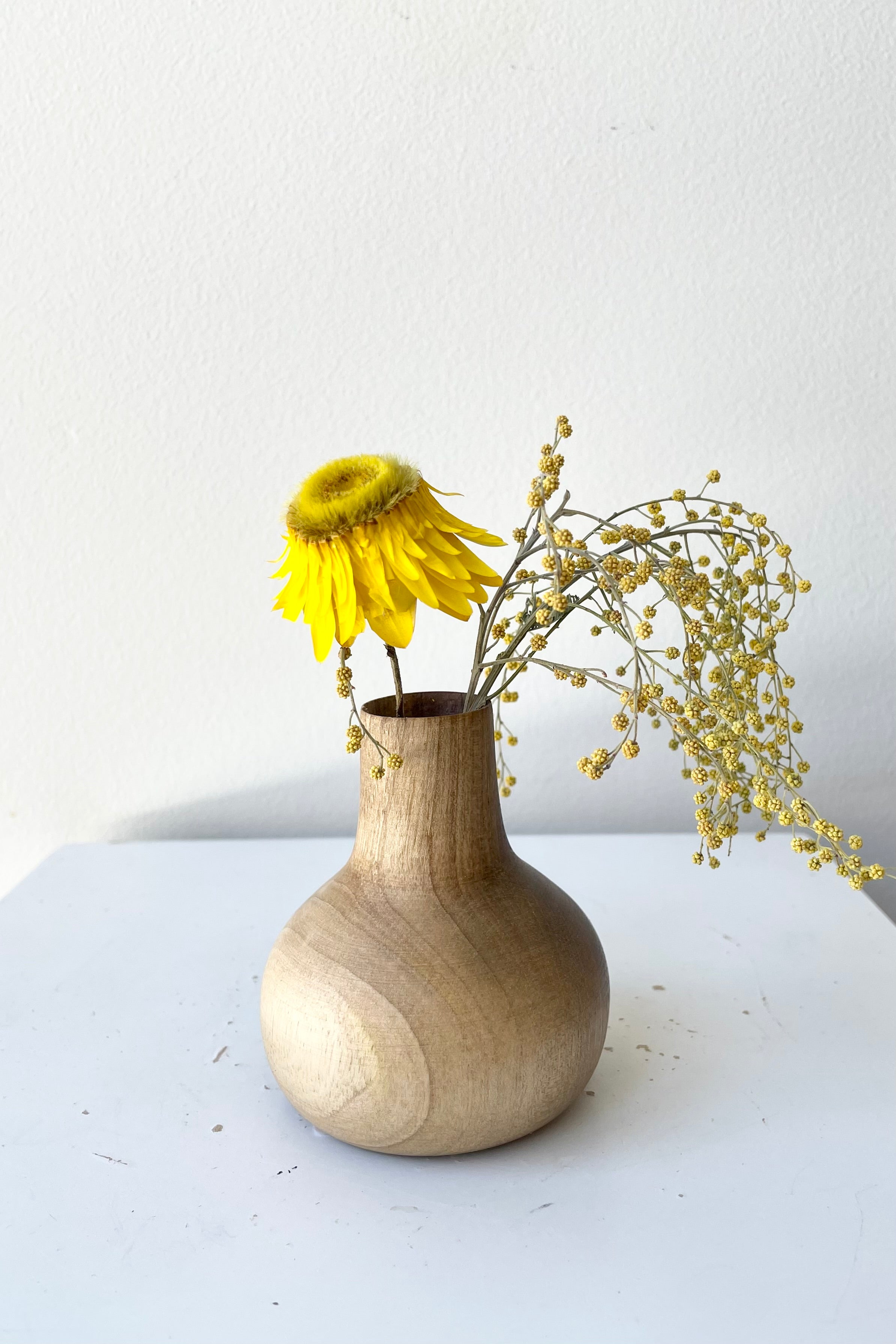 The walnut Nina wood vase against a white wall with dried floral at Sprout-home.
