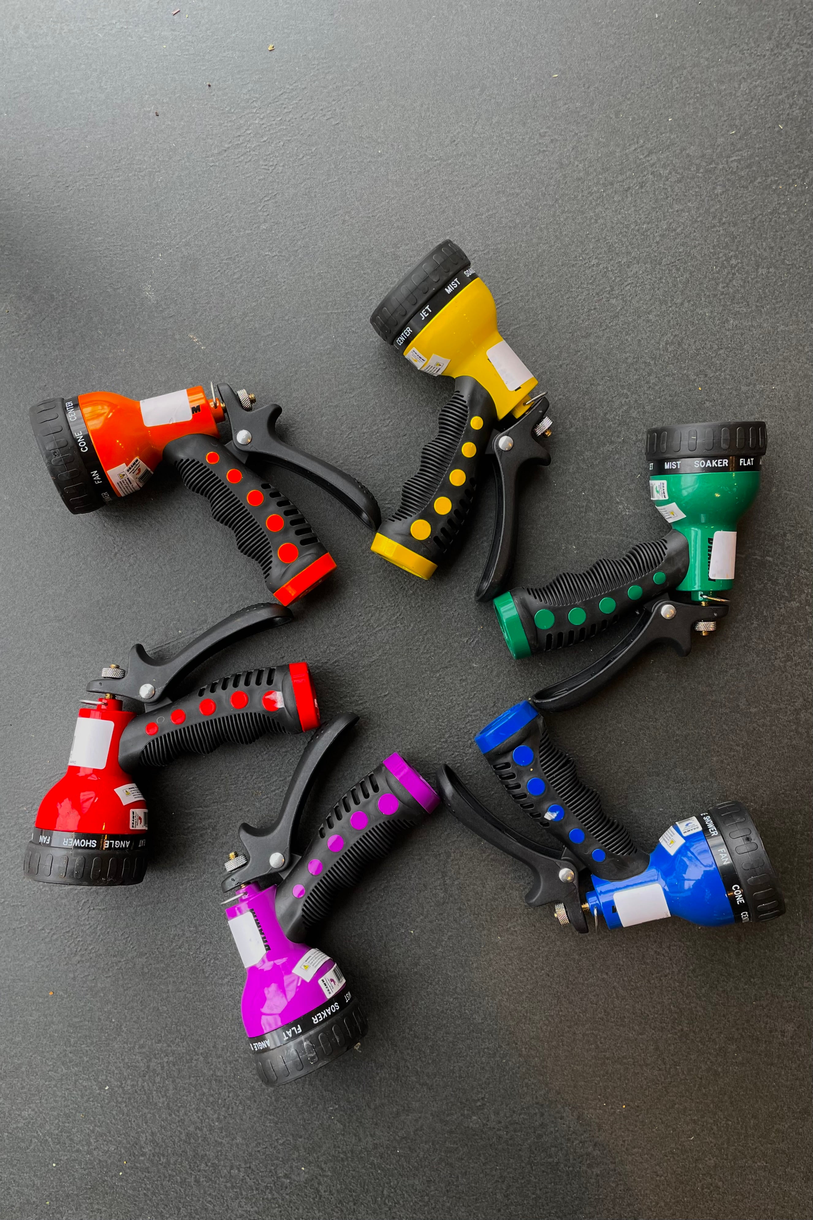 Dramm Touch 'N Flow Revolver Sprayer in red, orange, yellow, green, blue, and purple  against a black backdrop