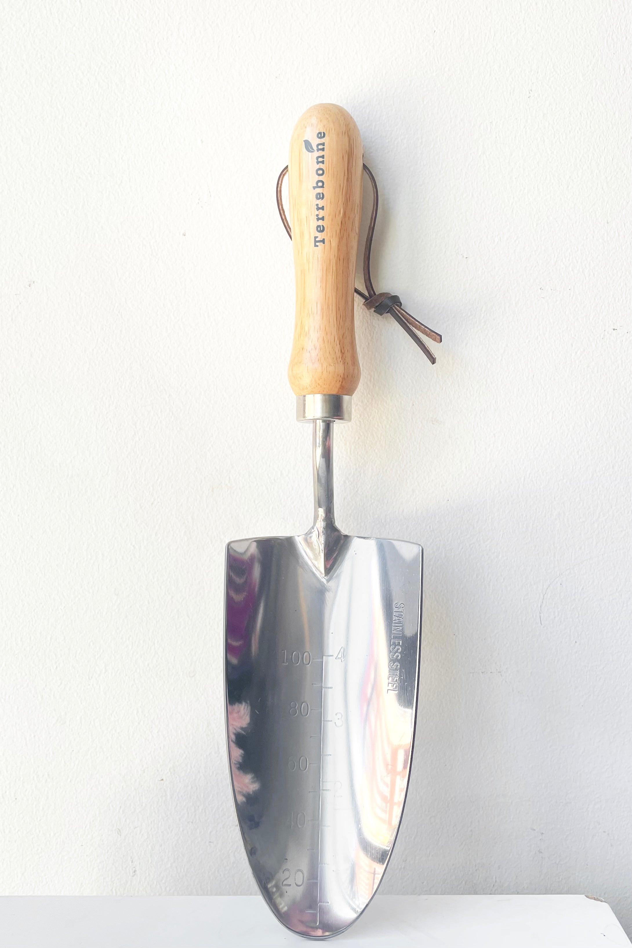 Hand Trowel rests upright against white wall on white pedestal 