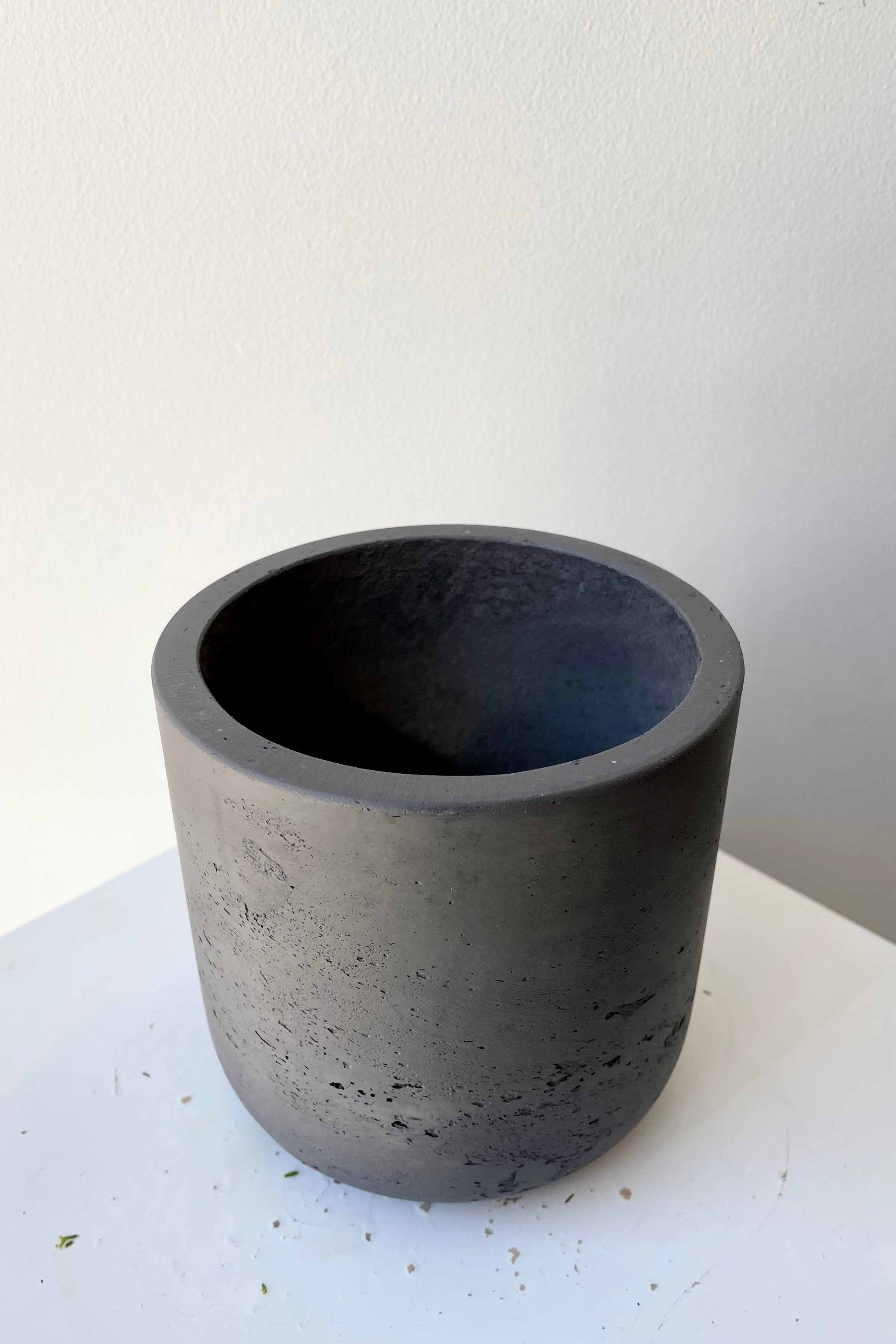 The black washed extra small Charlie pot against a white wall at Sprout-home. 