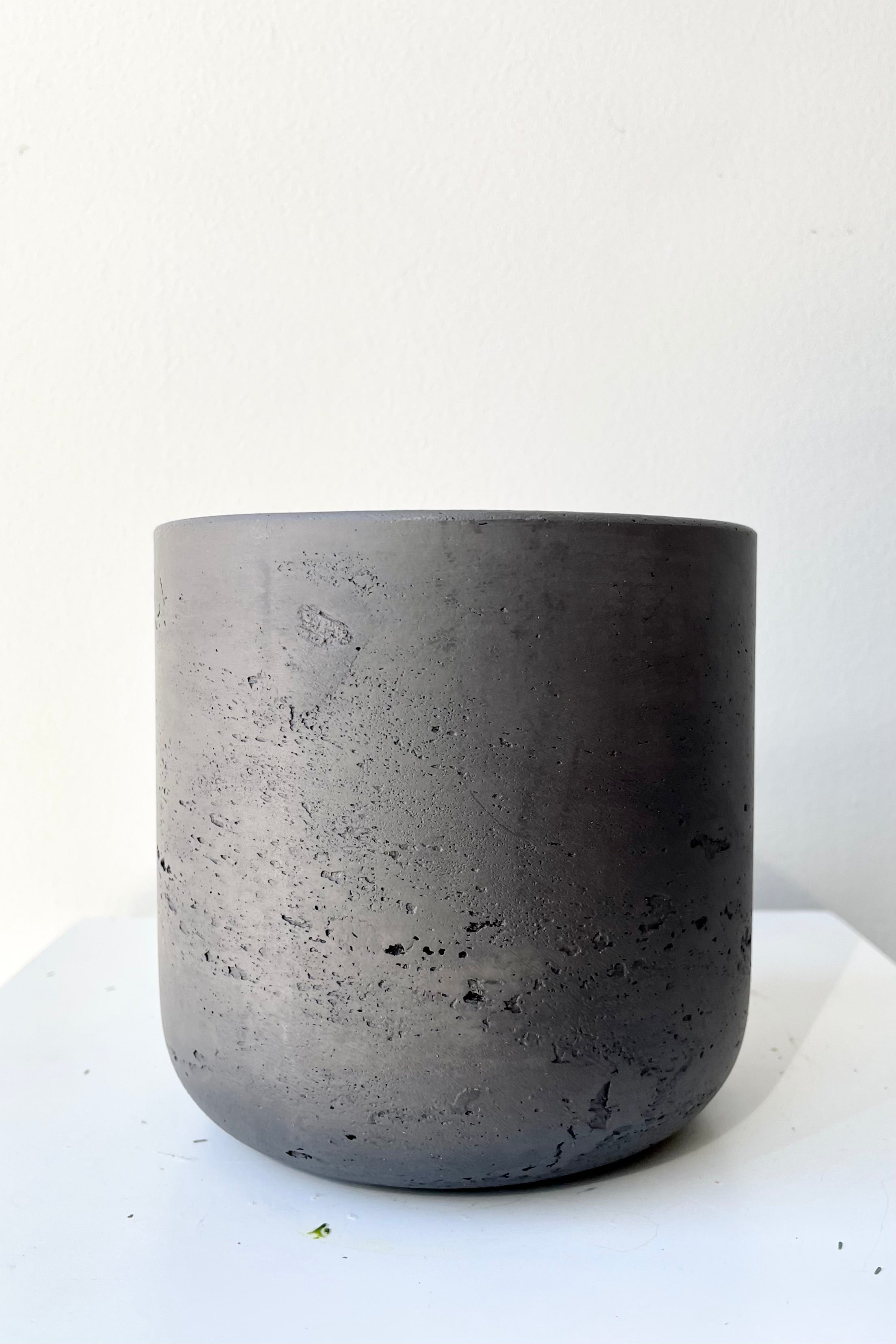 The black washed extra small Charlie pot against a white wall at Sprout-home. 