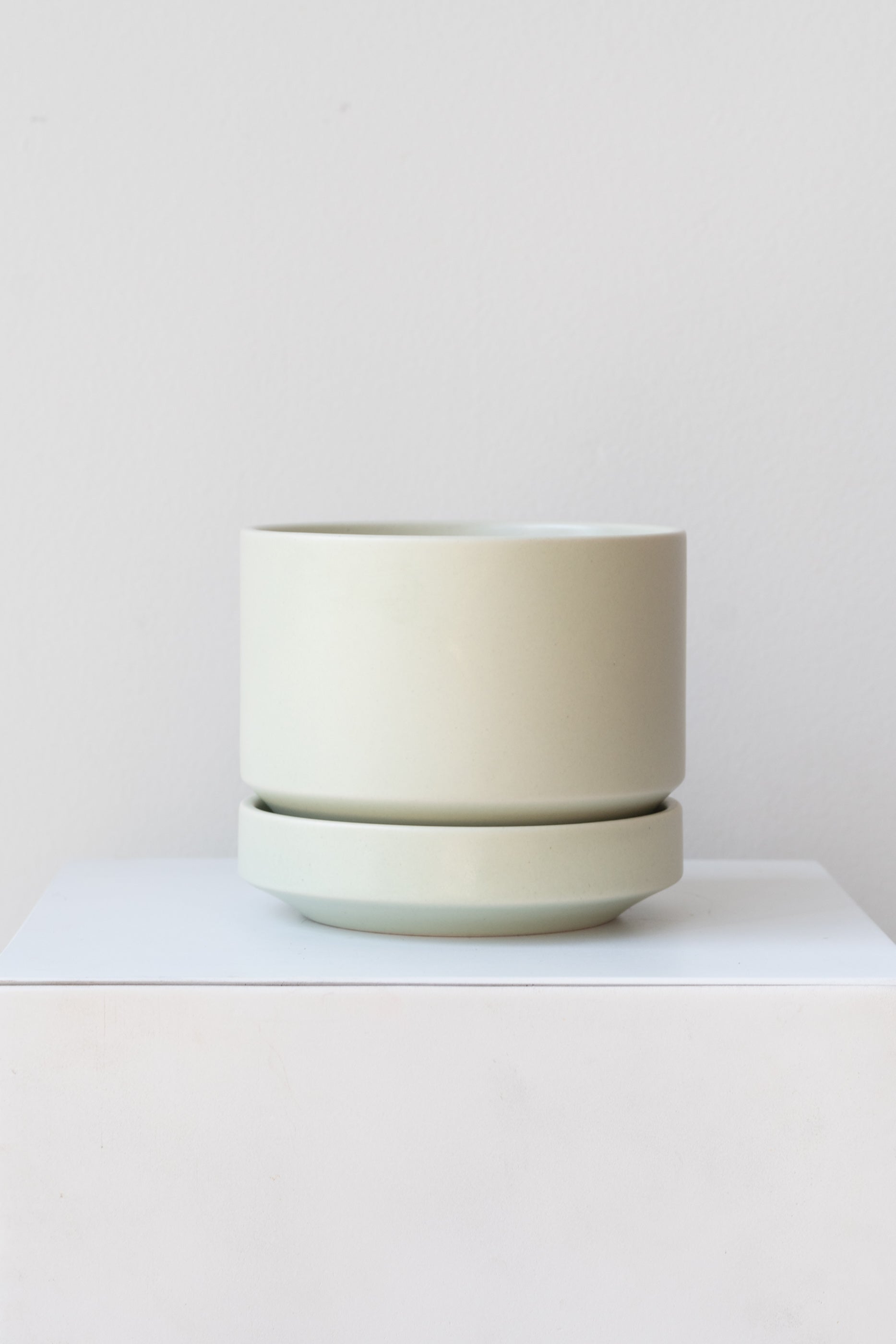 LBE Designs Round Pot & Saucer mint on a white pedestal in a white room