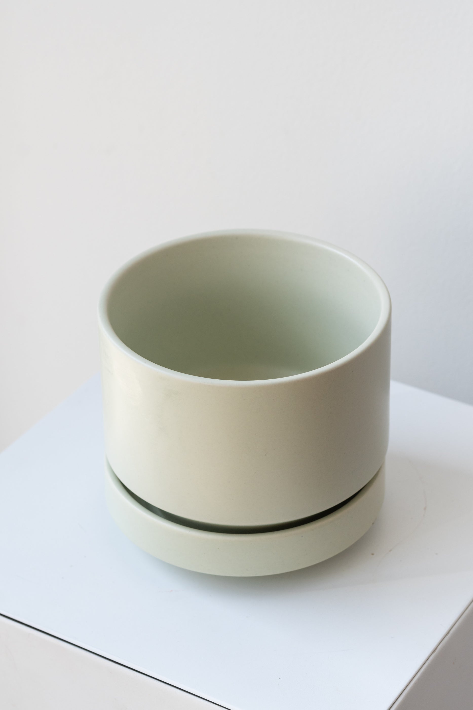LBE Designs Round Pot & Saucer mint on a white pedestal in a white room