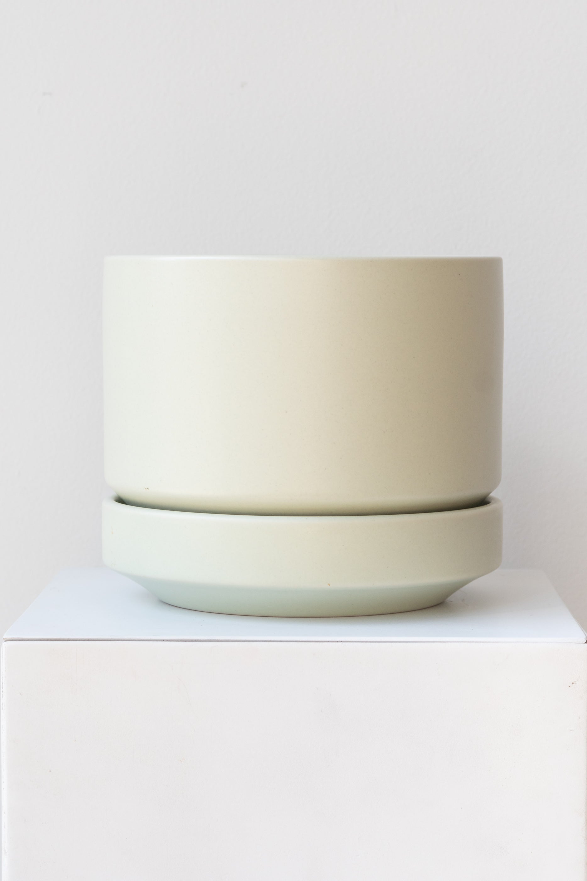 LBE Designs Round Pot & Saucer mint on a white pedestal in a white room
