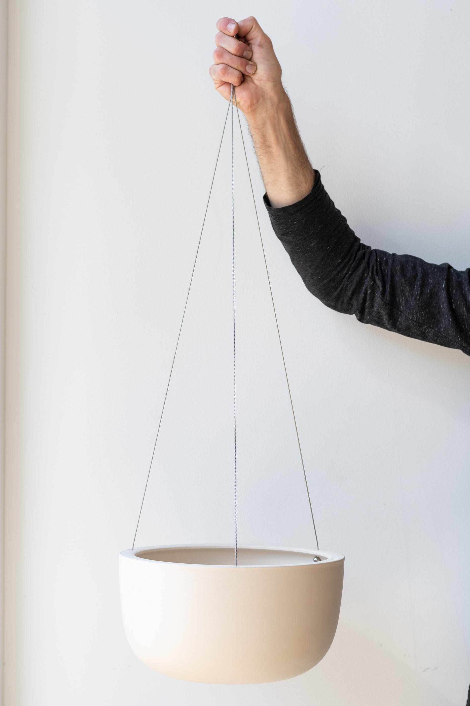Angus and Celeste Raw Earth Hanging Planter clay large held in front of white wall